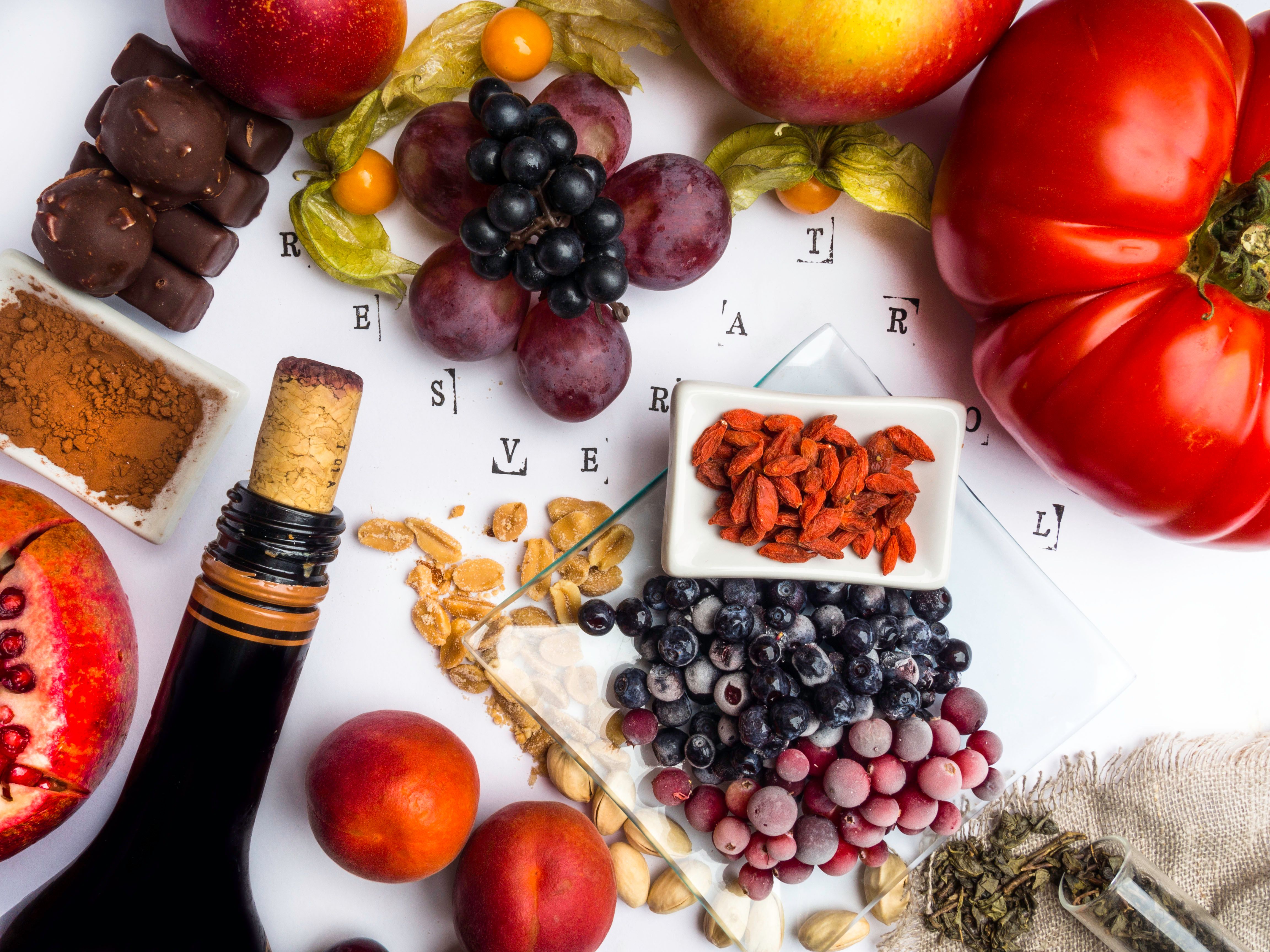 food rich with resveratrol, grapes, pomegranate, green tea on sackcloth, physalis, cranberry, cherry, tomatoes, goji, peanuts, blueberry dark chocolate, cocoa, red wine