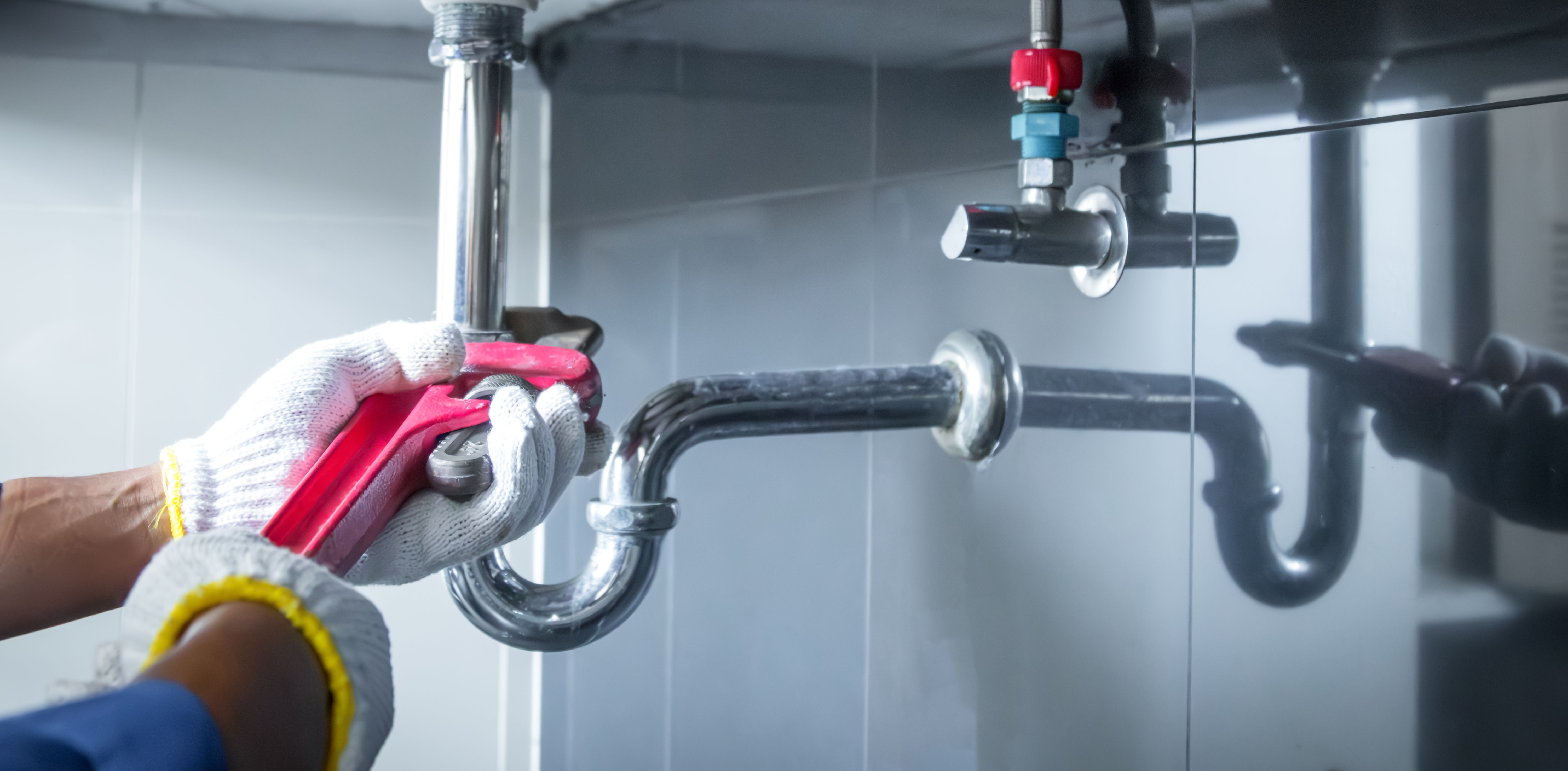 Plumber hands holding wrench doing repairing work at the sink and clogged pipe in bathroom carefully