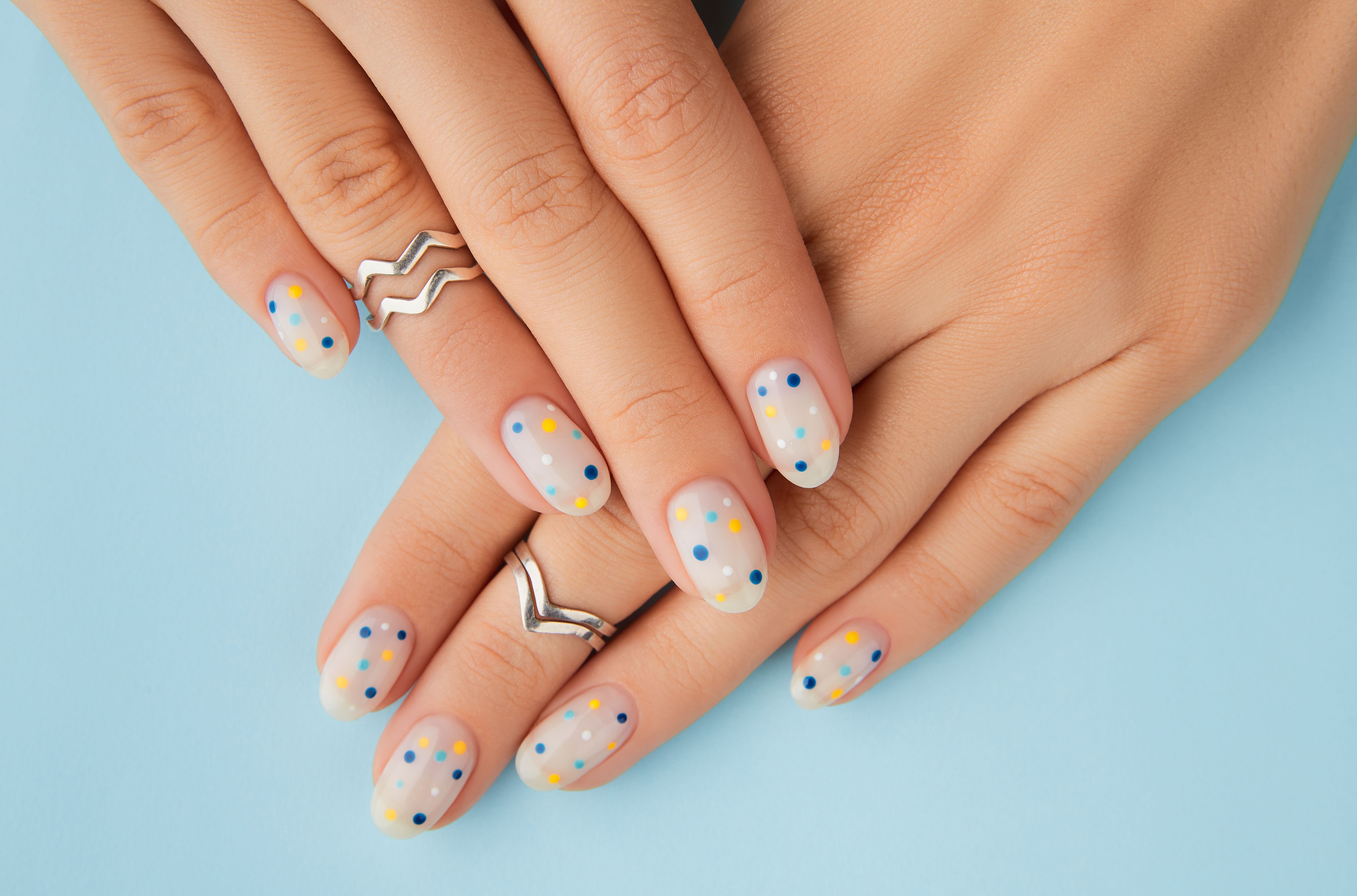 Womans hands with trendy polka dot summer manicure