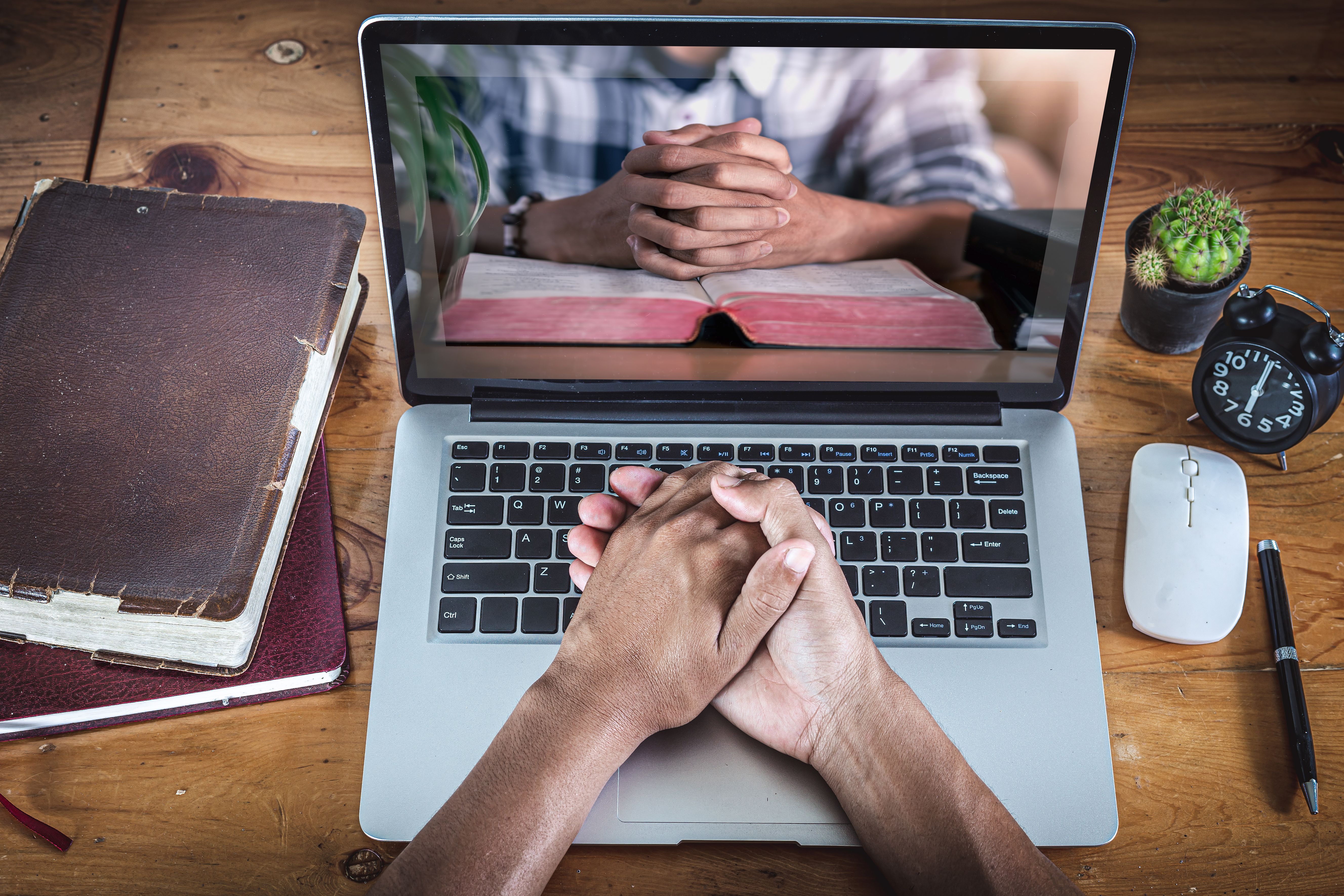 Hands praying with computer laptop, Online live church for sunday service, Home church during quarantine coronavirus Covid-19, Religion concept