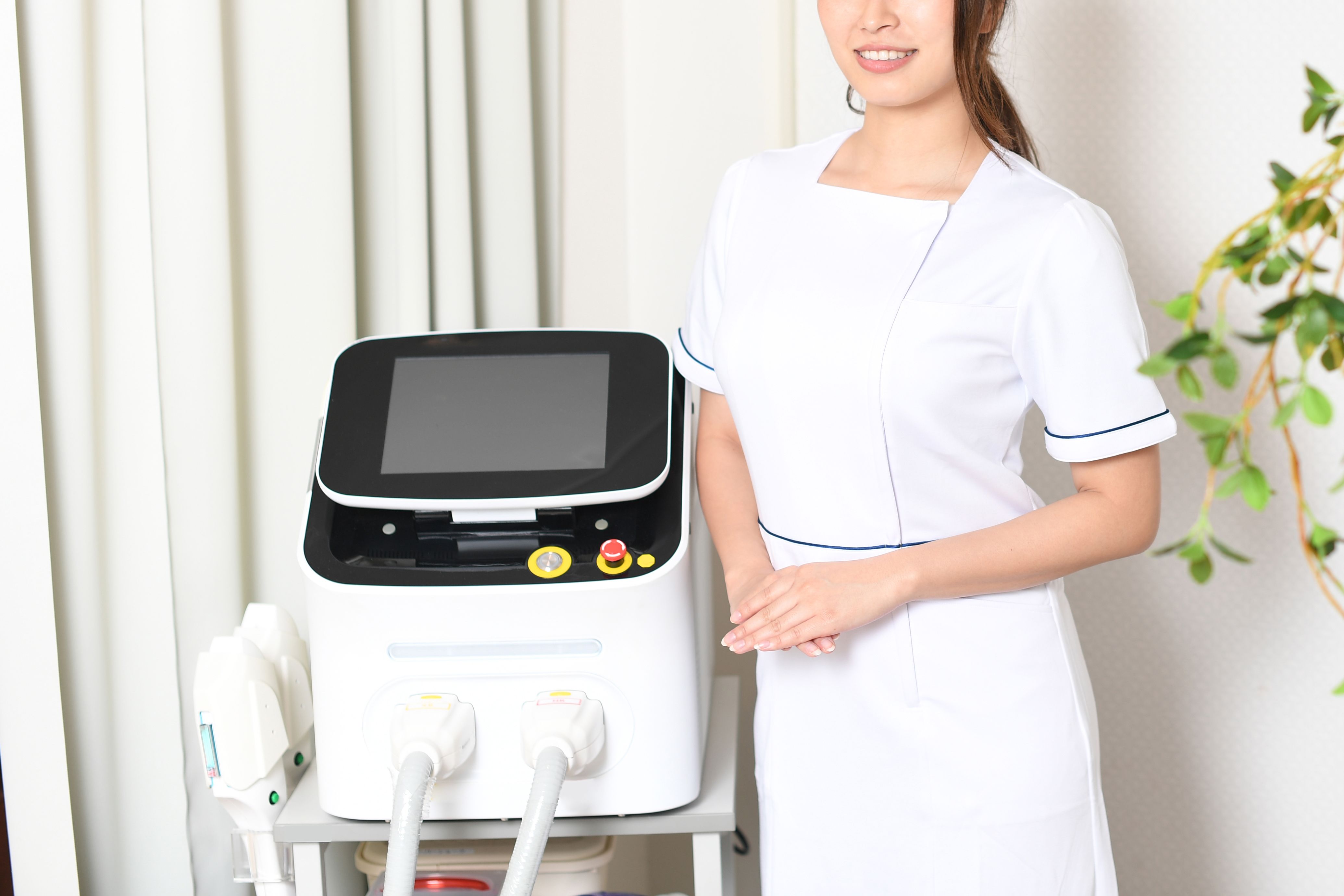 A young Asian woman working as a salon staff is in front of a laser hair removal device