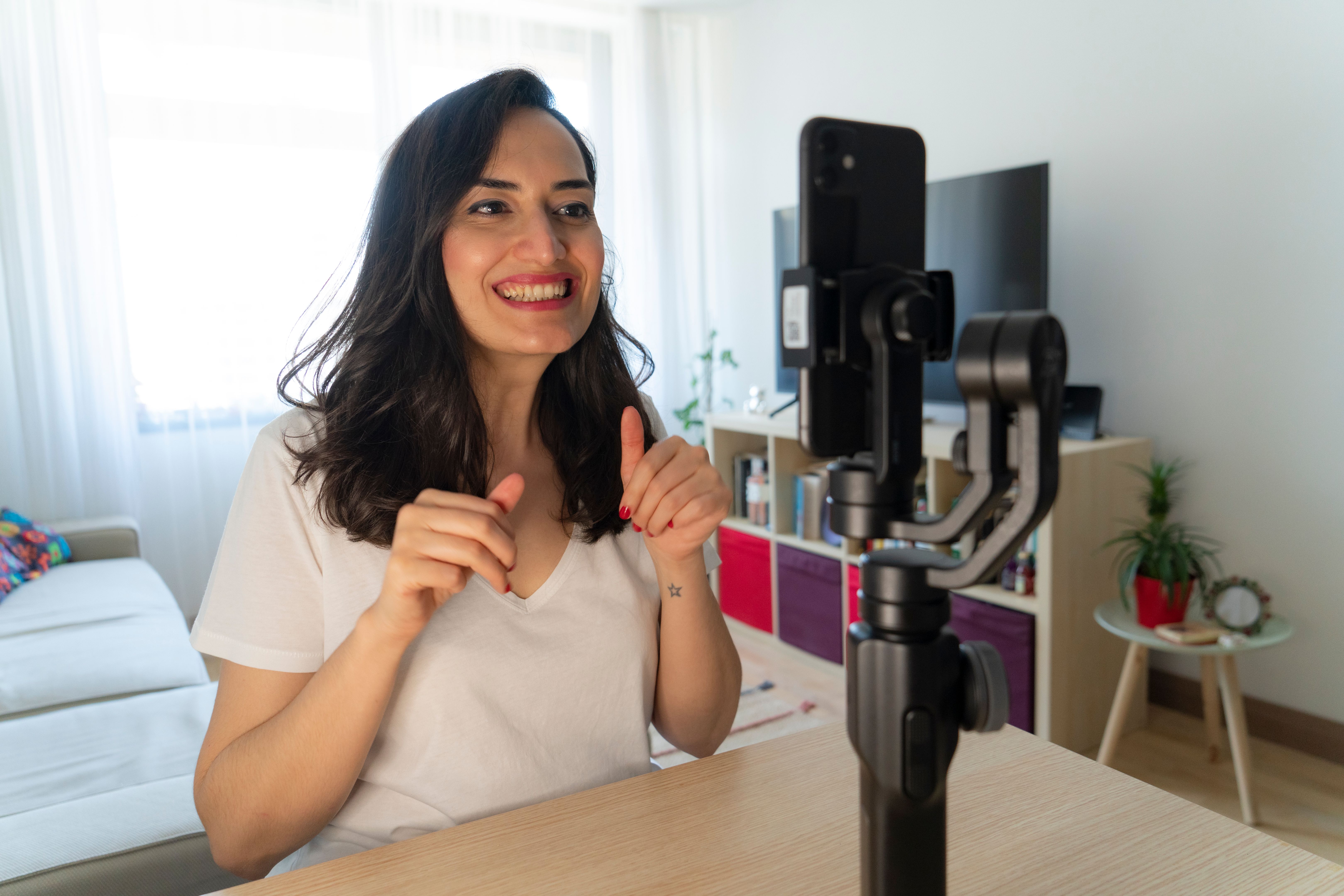 Woman using mobile phone recording video live streaming online at home