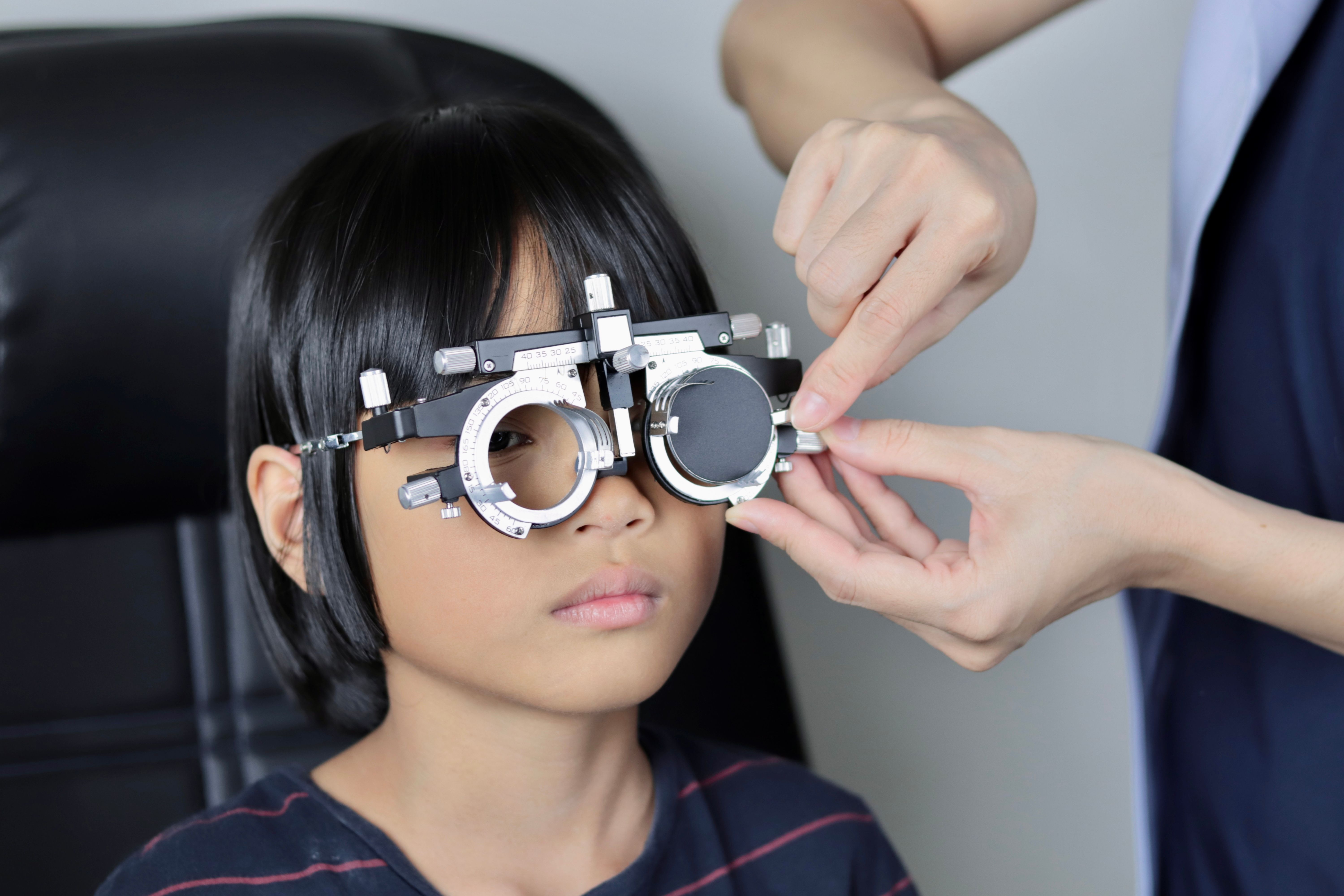 Elementary school girl wearing eyeglasses visual acuity test with test chart, eye test, Female patient checking eyesight in ophthalmology clinic, eye check