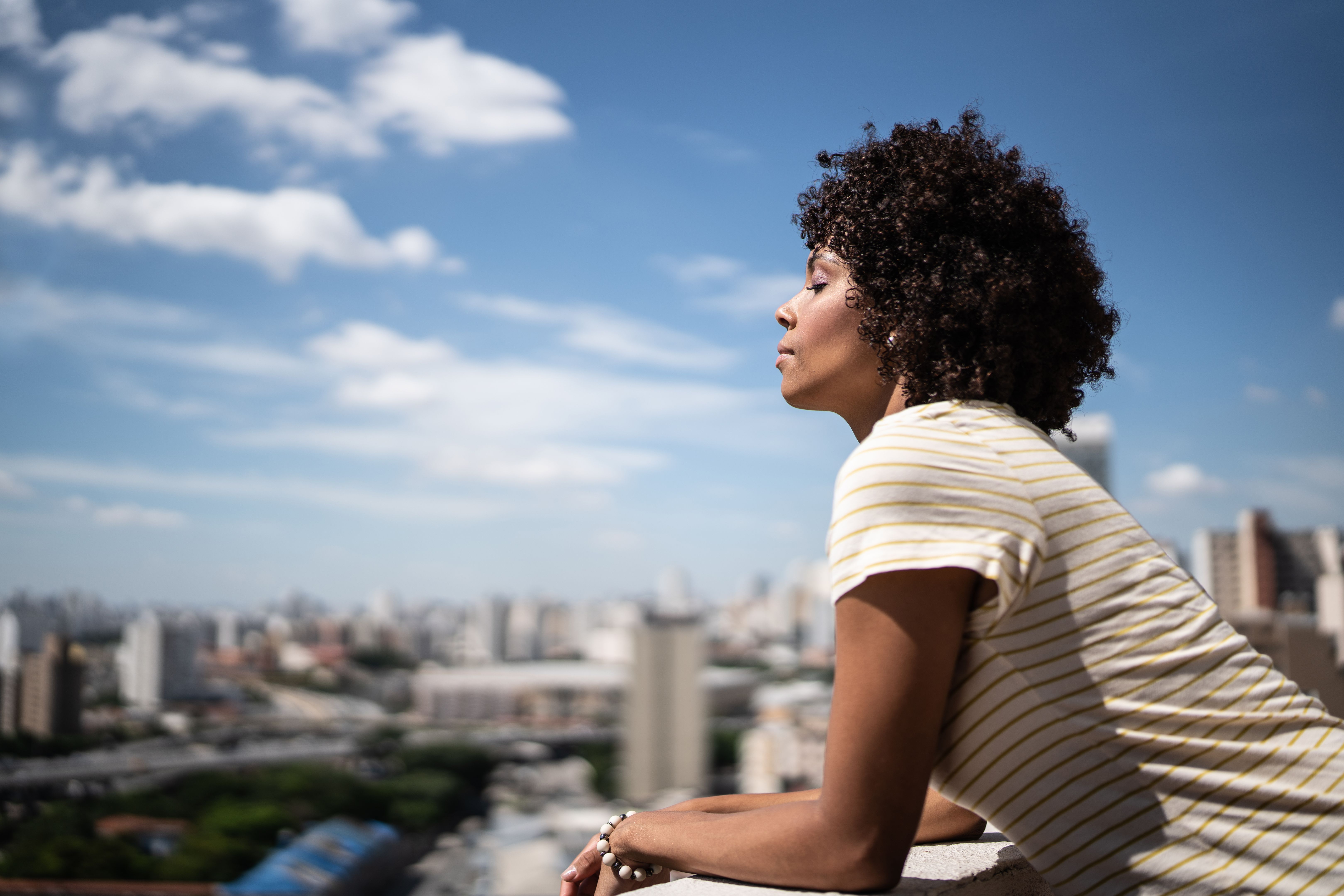 Young woman breathing with eyes closed on apartment's balcony