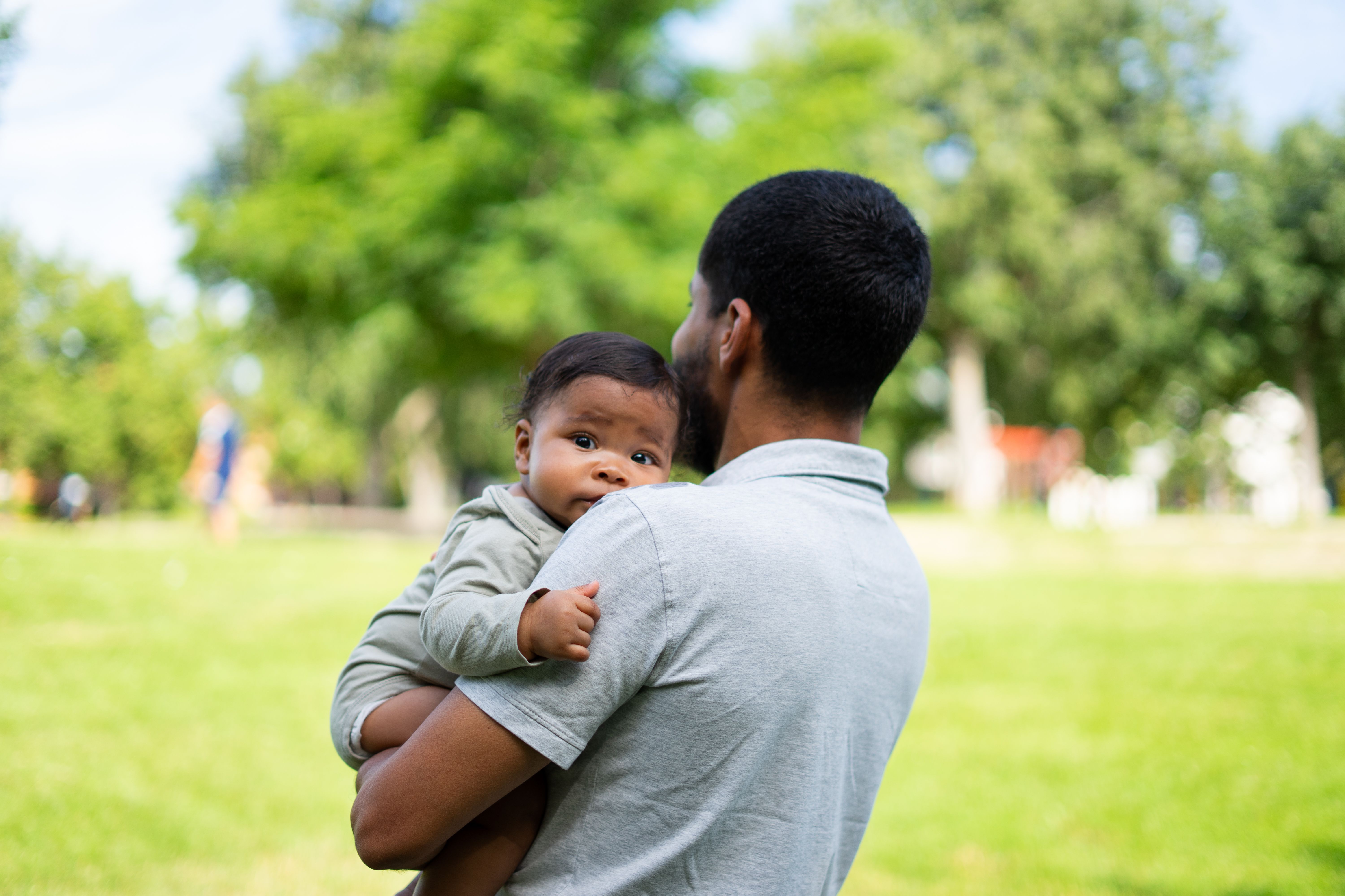 Bebé latino en brazos de su padre en un parque