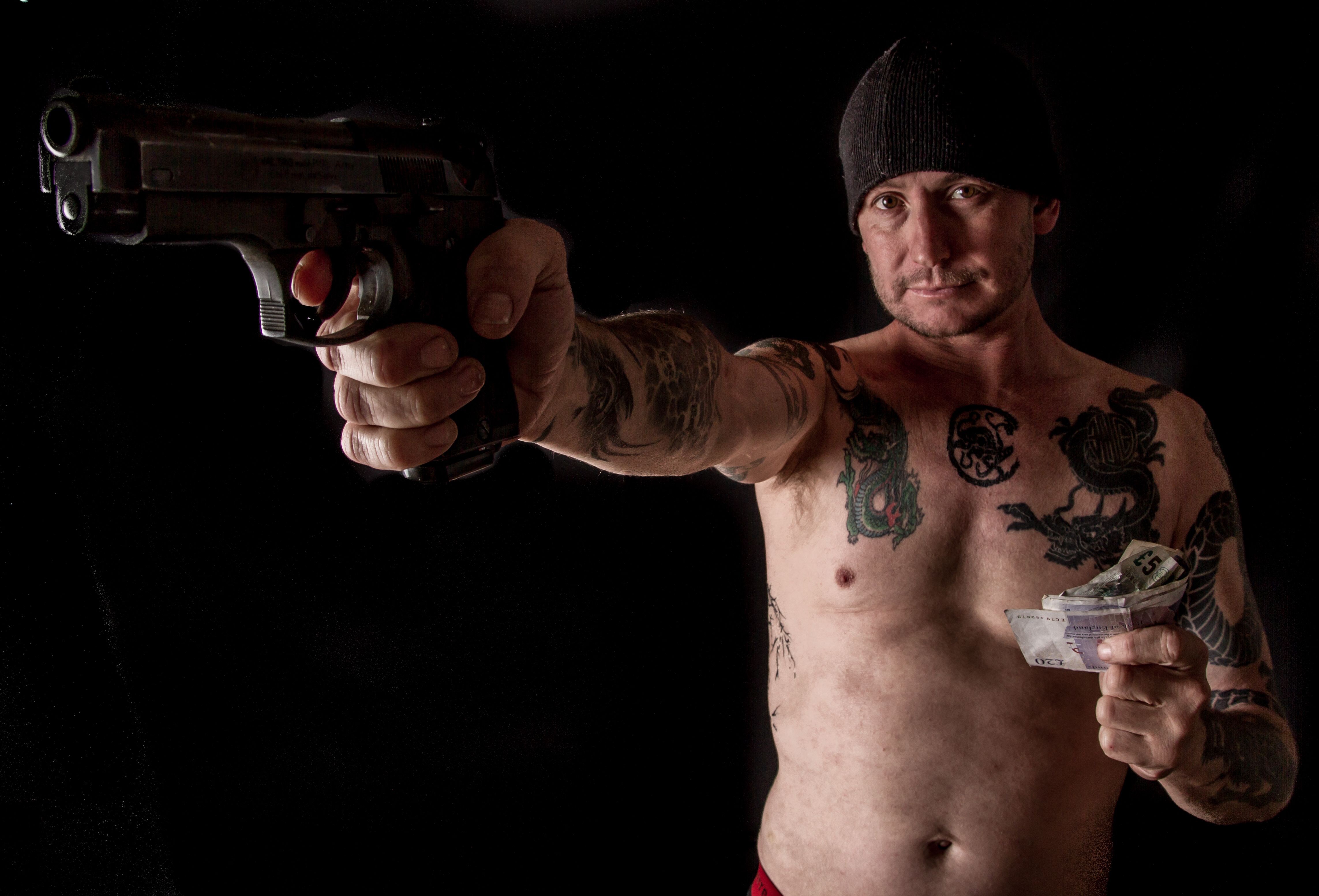Tattooed man with gun and cash