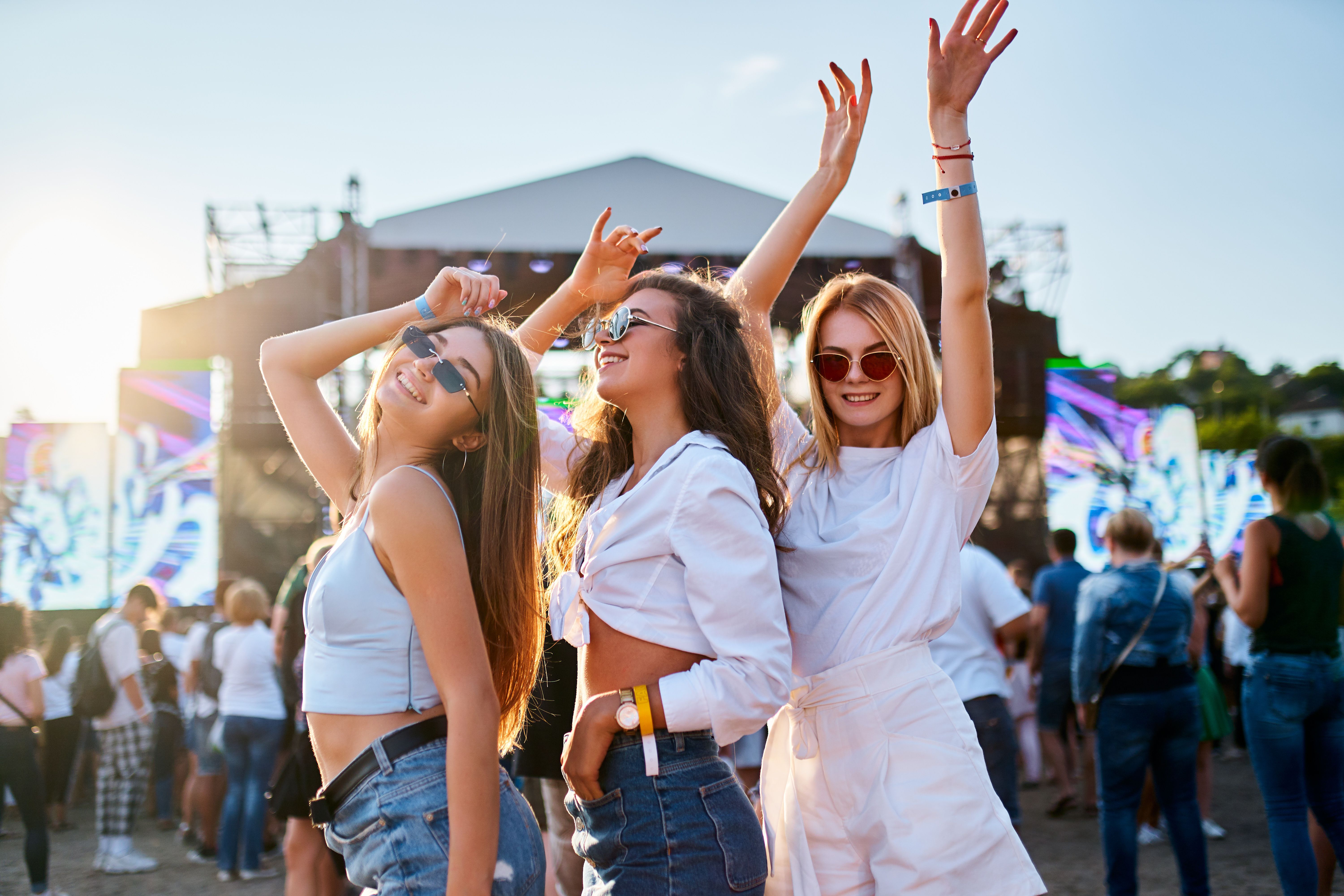 Group of young women enjoying at a beach music festival, dancing together in summer outfits with sunglasses. Sunlight illuminates the happy crowd, friends celebrate, party atmosphere by the ocean. Group of young women enjoying at a beach music festival, dancing together in summer outfits with sunglasses. Sunlight illuminates the happy crowd, friends celebrate, party atmosphere by the ocean.