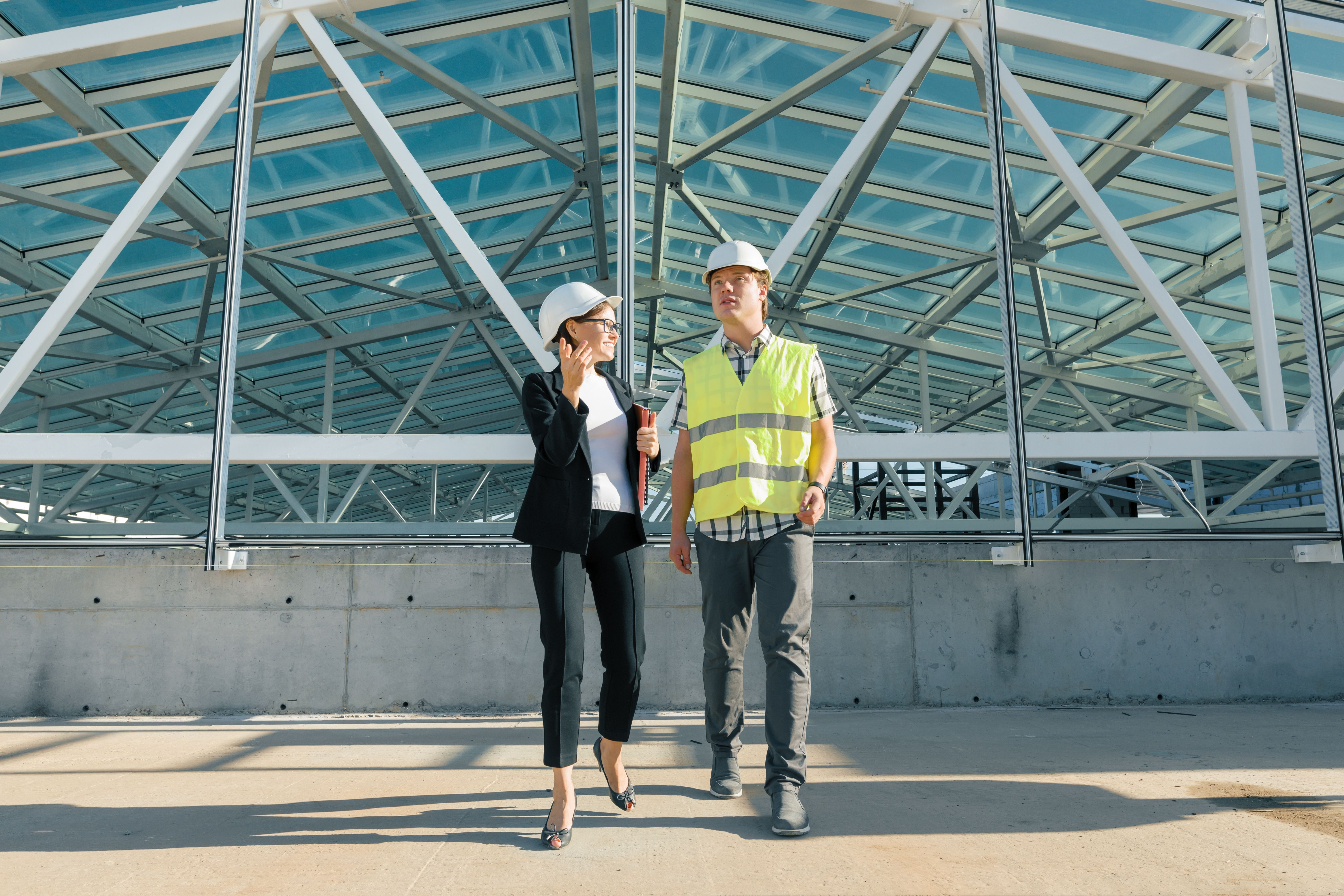 Woman engineer and man builder at construction site. Building, development, teamwork and people concept