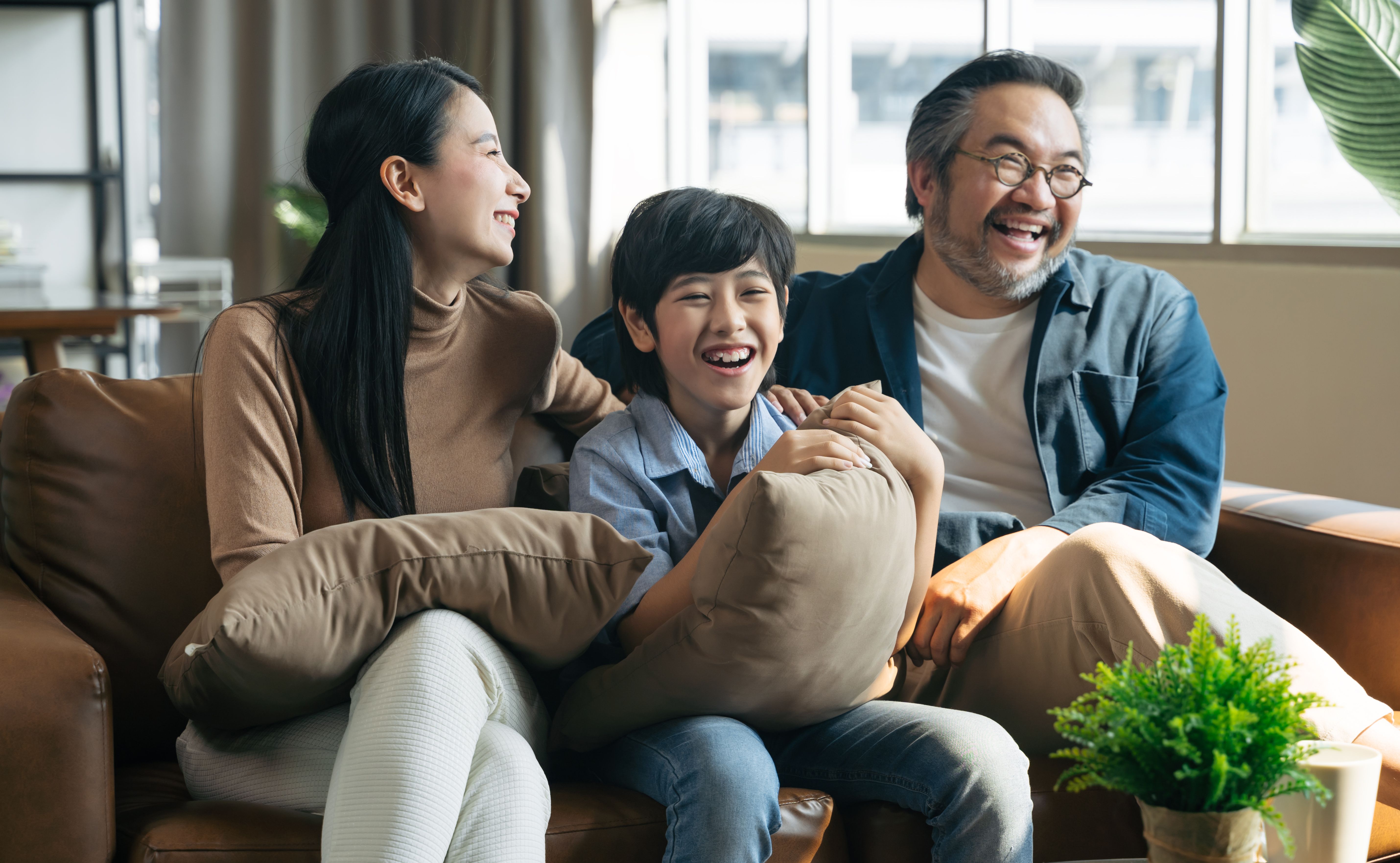 Happy Asian family spending time by watching tv together on sofa in living room. family and home concept Happy Asian family spending time by watching tv together on sofa in living room. family and home concept