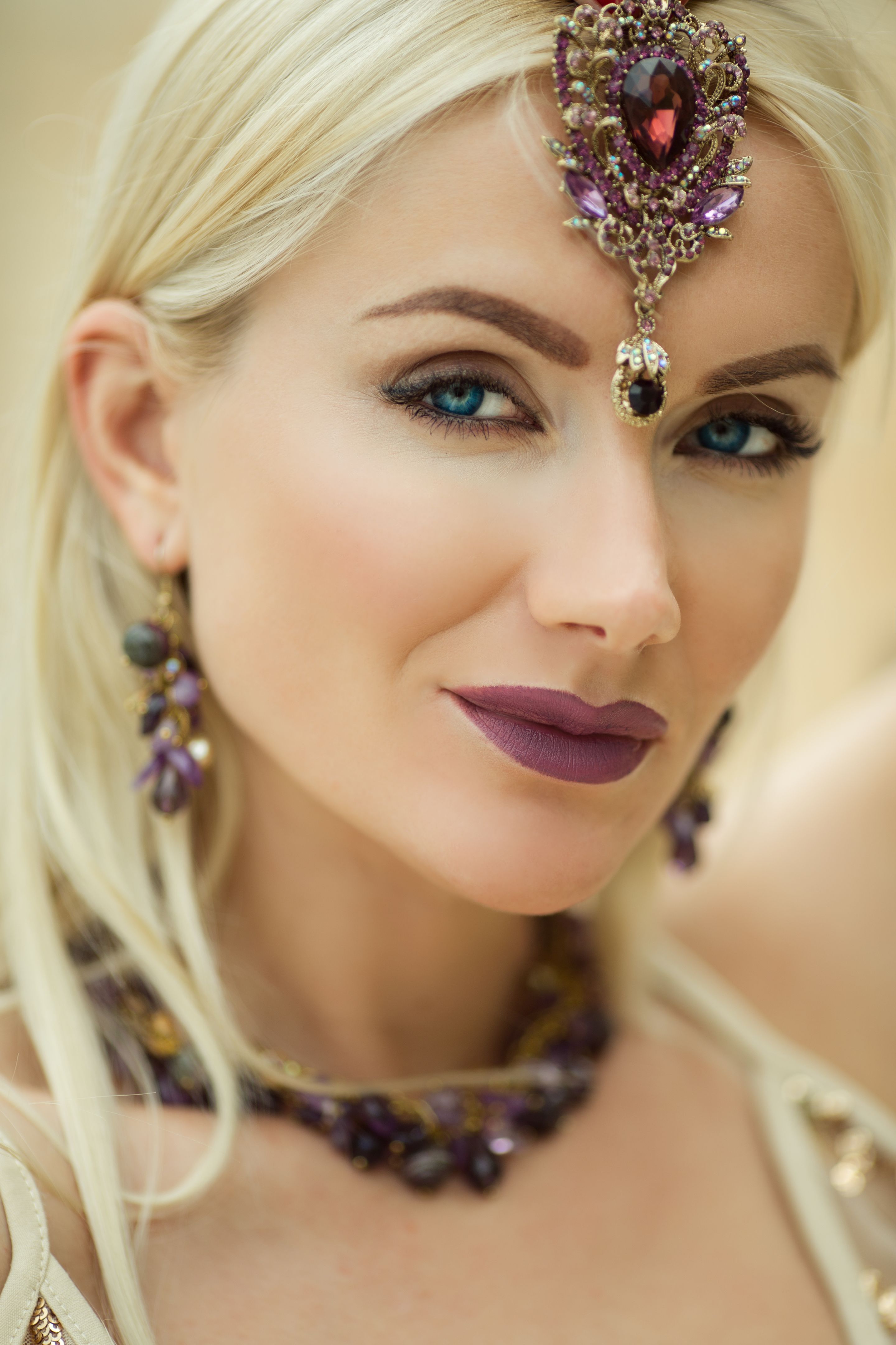 Beautiful closeup portrait of woman with a lilac make-up and manicure on nails is wearing jewelry with purple stones