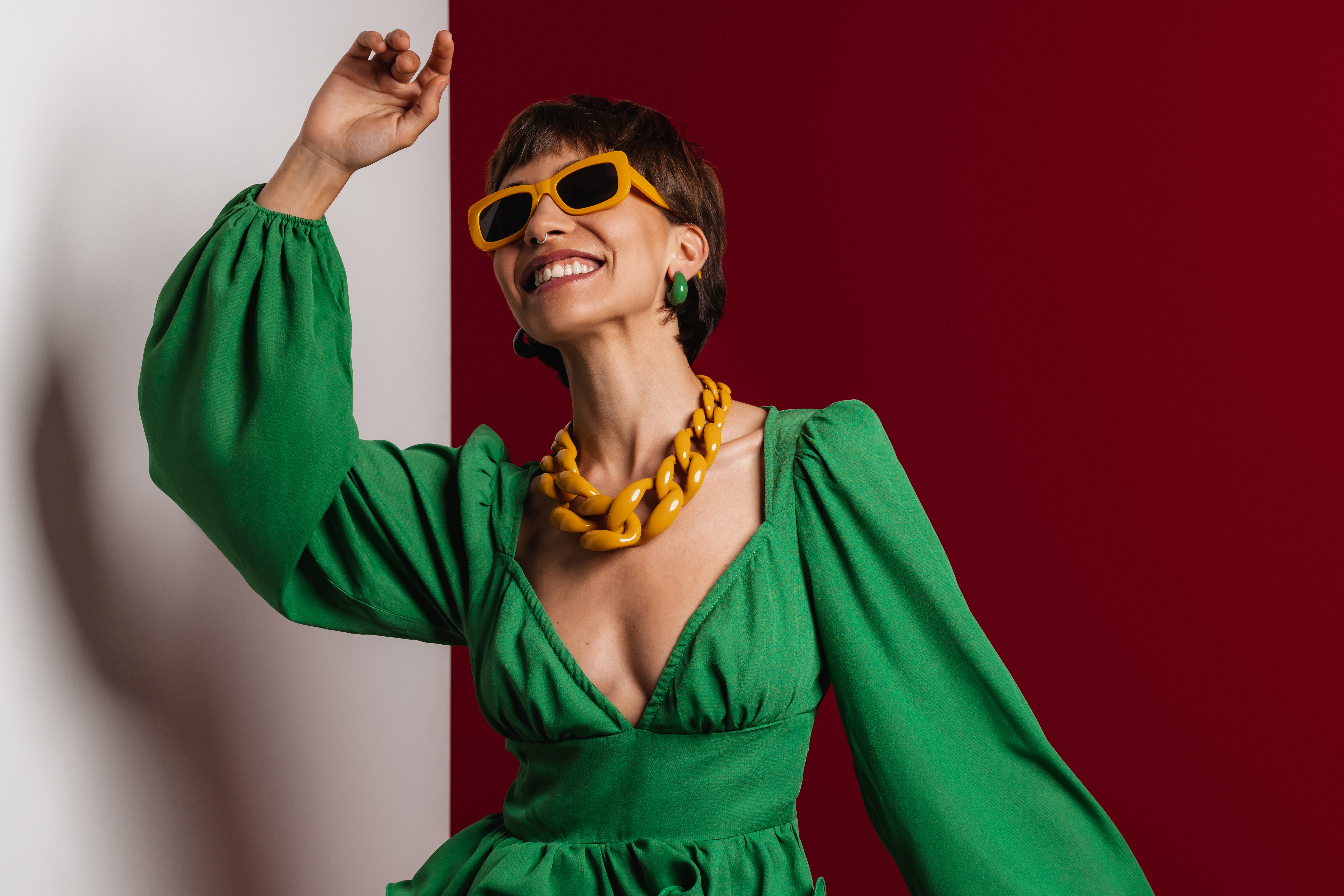 Happy young short hair woman in elegant dress dancing against red and white background