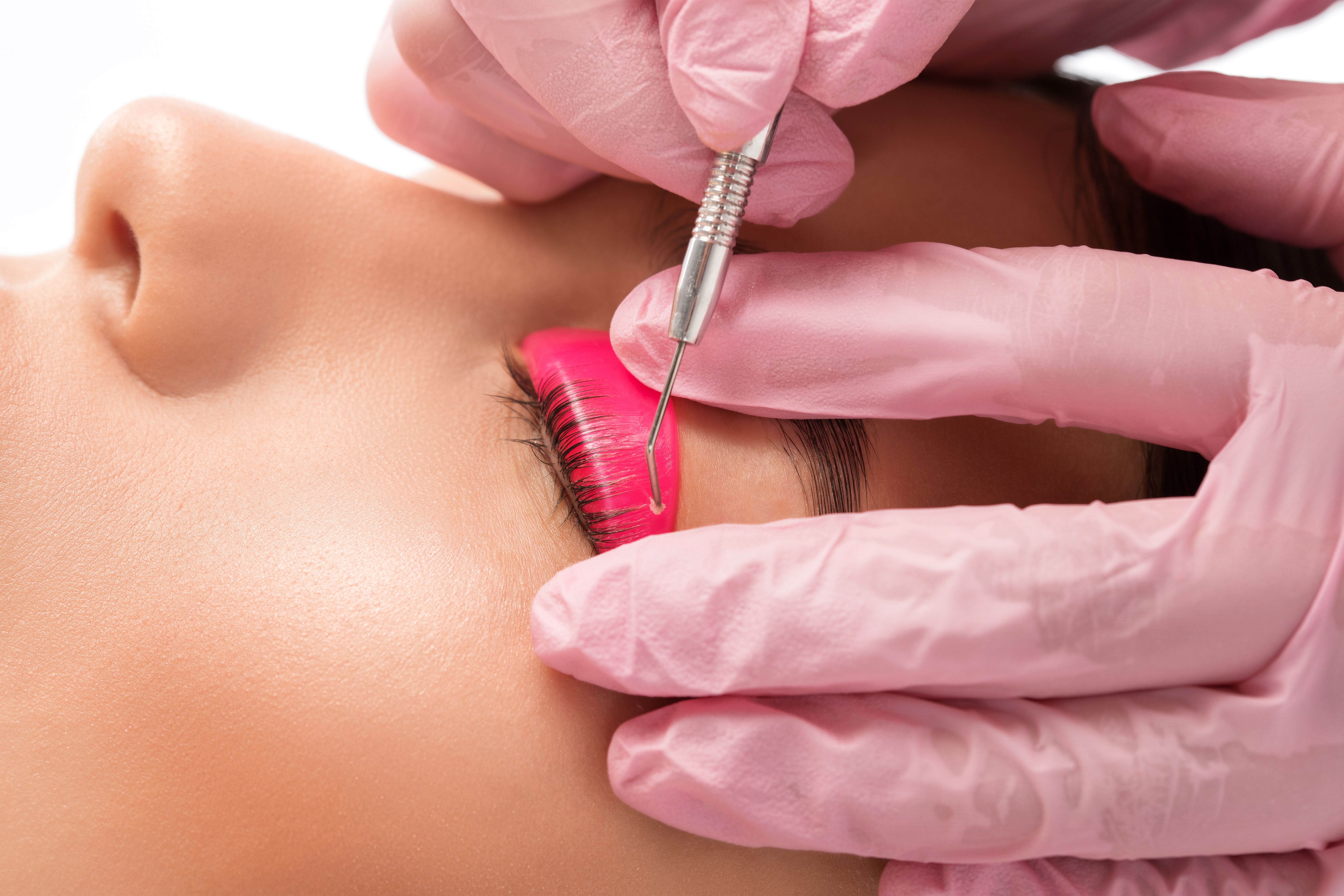 Make-up artist makes the procedure of lamination and dyeing of eyelashes to a beautiful woman in a beauty salon. Eyelash extensions. Eyelashes close-up