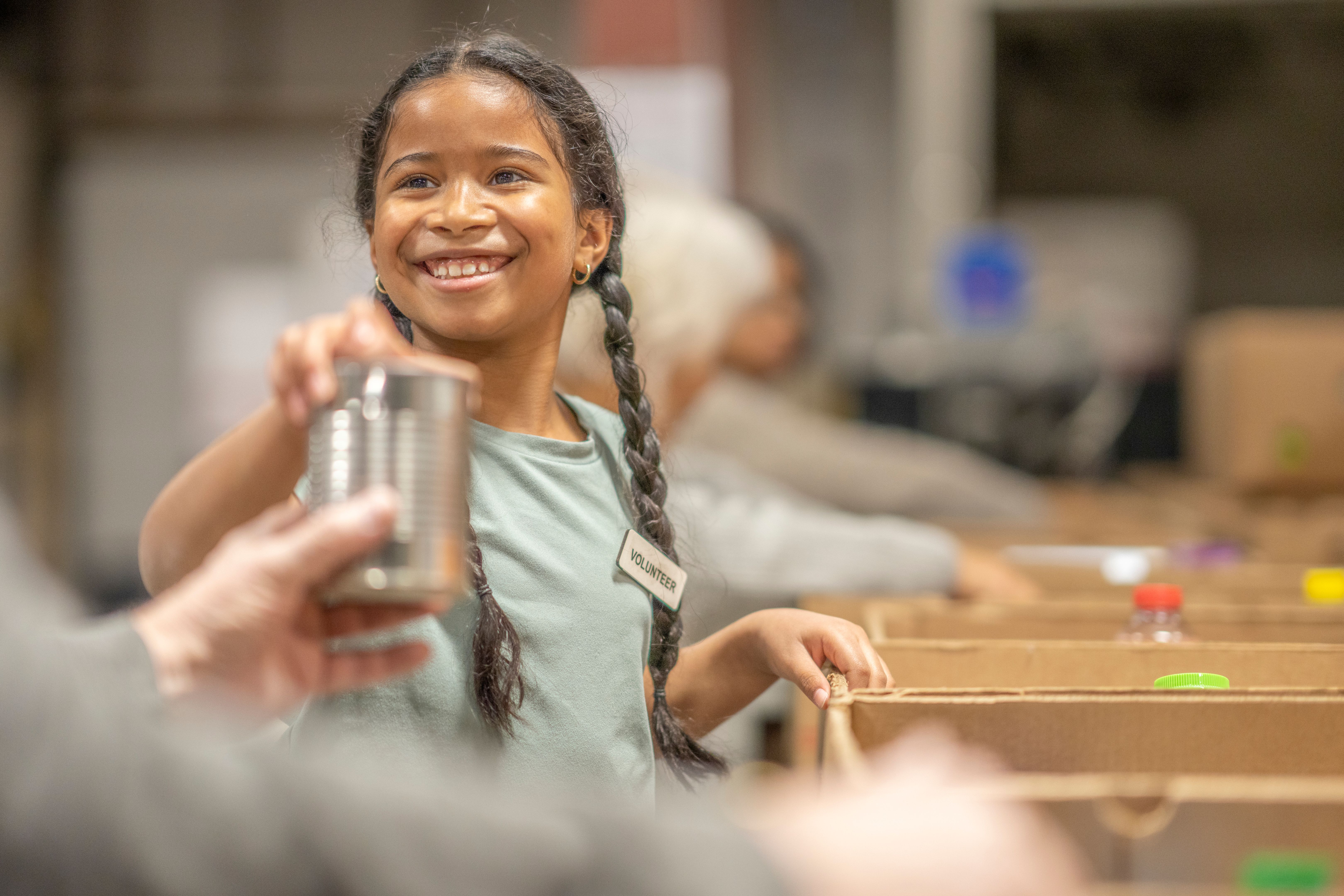 Smiling volunteer distributing canned goods at a Florida nonprofit fundraising event, supporting charitable solicitation compliance and donor transparency.