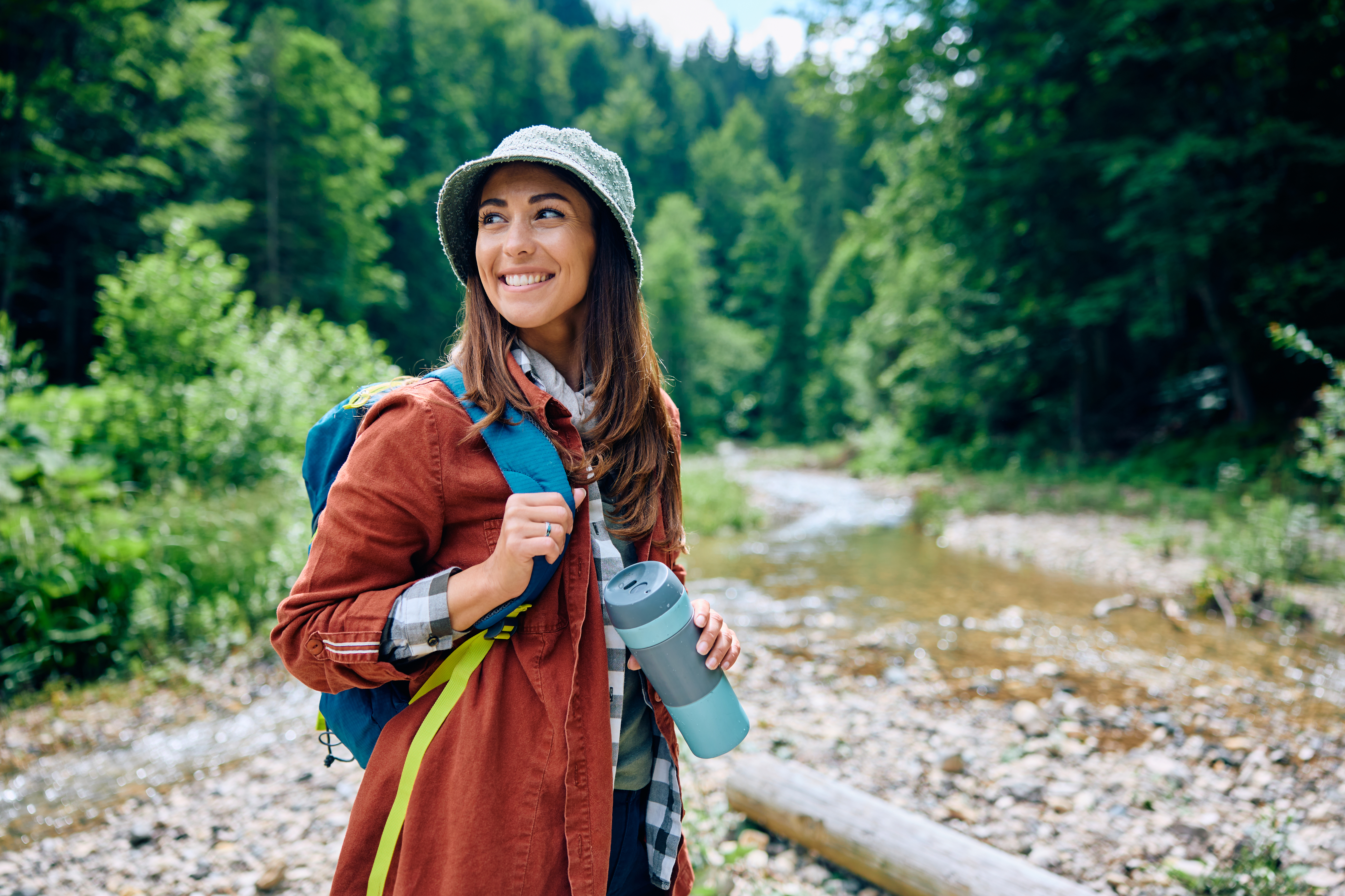 Happy woman enjoying in hiking in the woods and looking away.