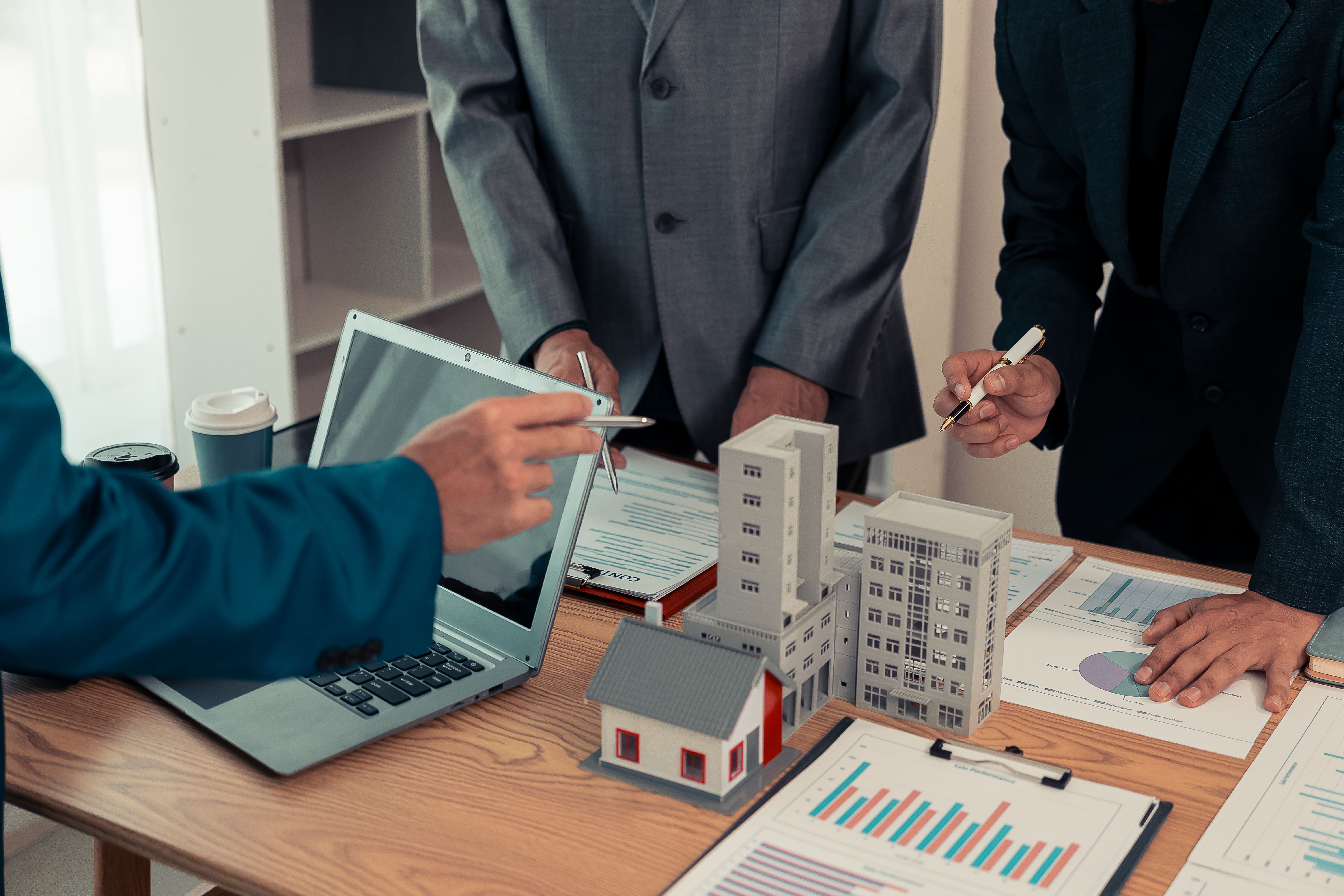 Real estate entrepreneurs meeting to sell a house, discussing real estate deals, with house plans on the table, symbolizing real estate investment and negotiations.
