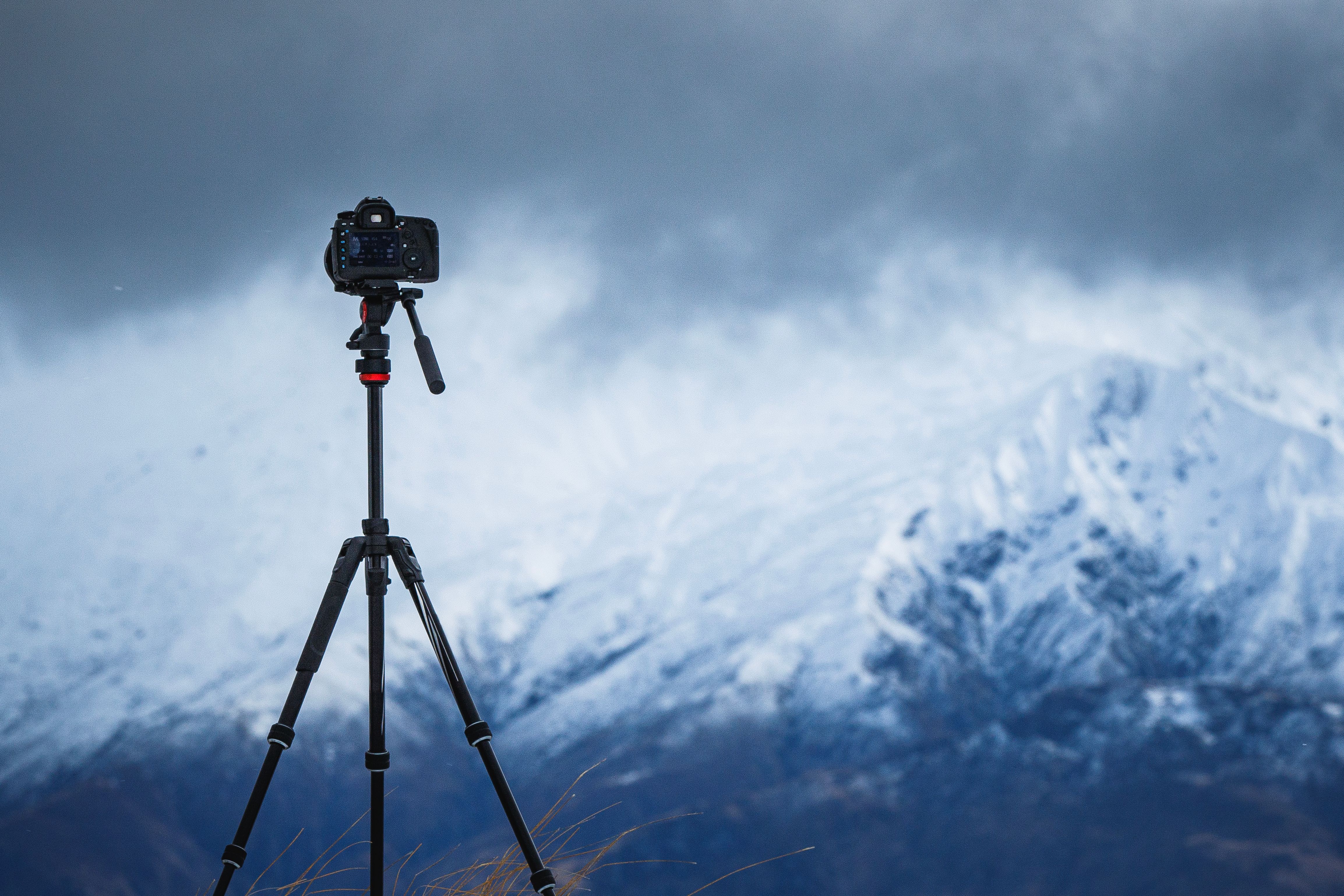 Equipamento de câmera na configuração do tripé tirando fotografias da paisagem dramática da montanha