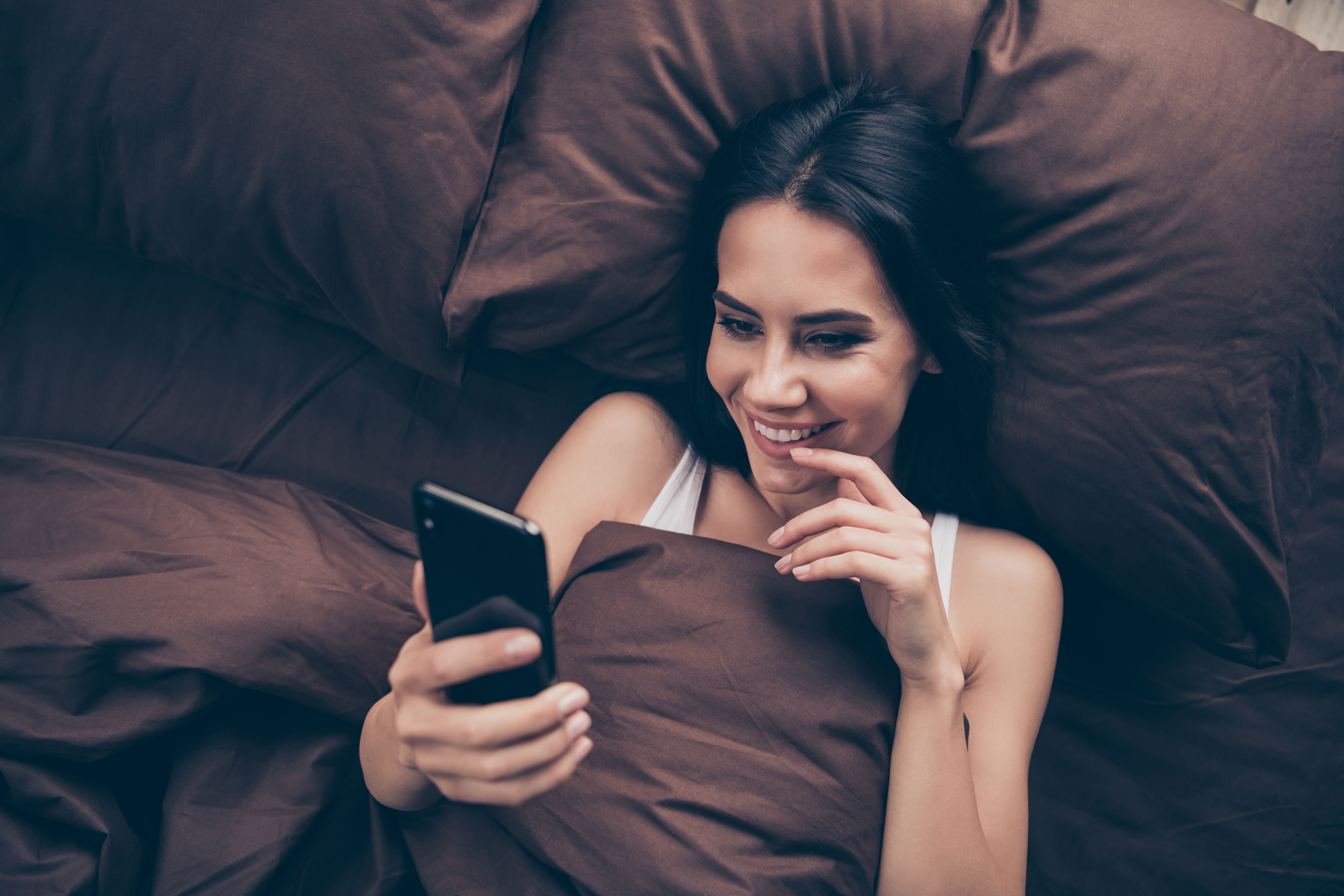 Top above high angle view close-up portrait of her she nice attractive lovely flirt charming cute cheerful cheery girl using gadget sending photos lying in bed in room flat house indoors