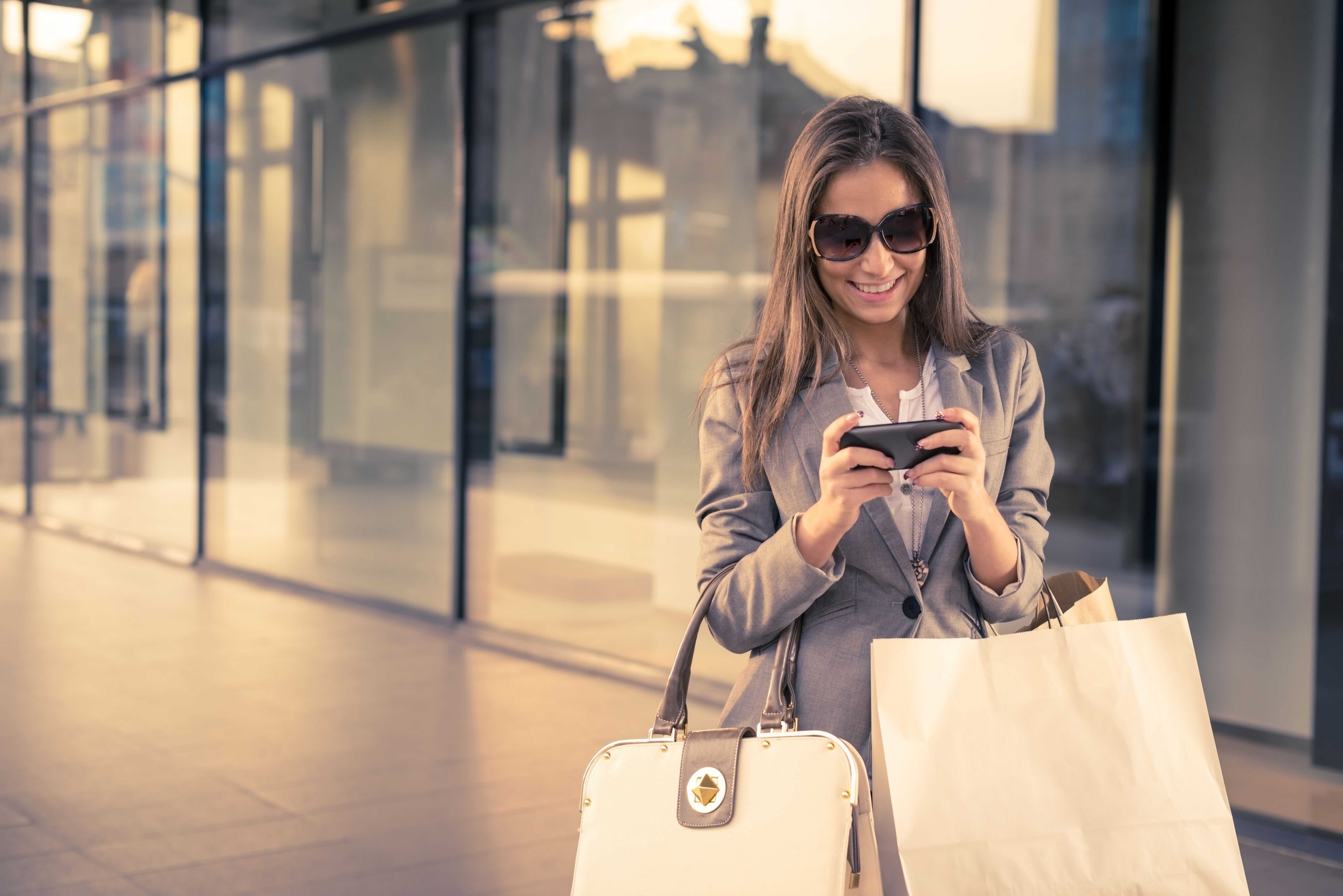 Smiling girl with shopping bags, texting