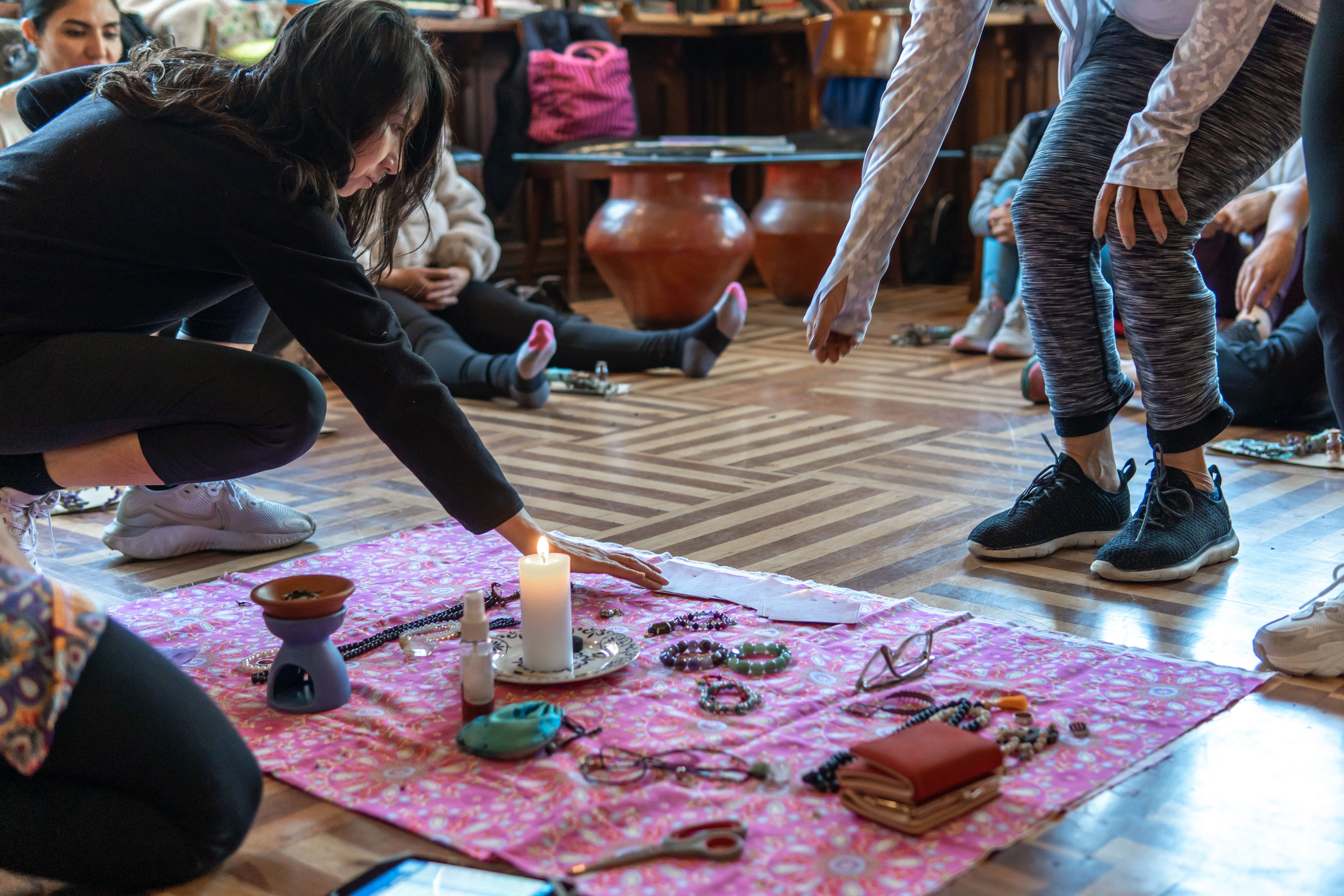 Women placing objects around a candle on a blanket for a ceremony of intent Women placing objects around a candle on a blanket for a ceremony of intent