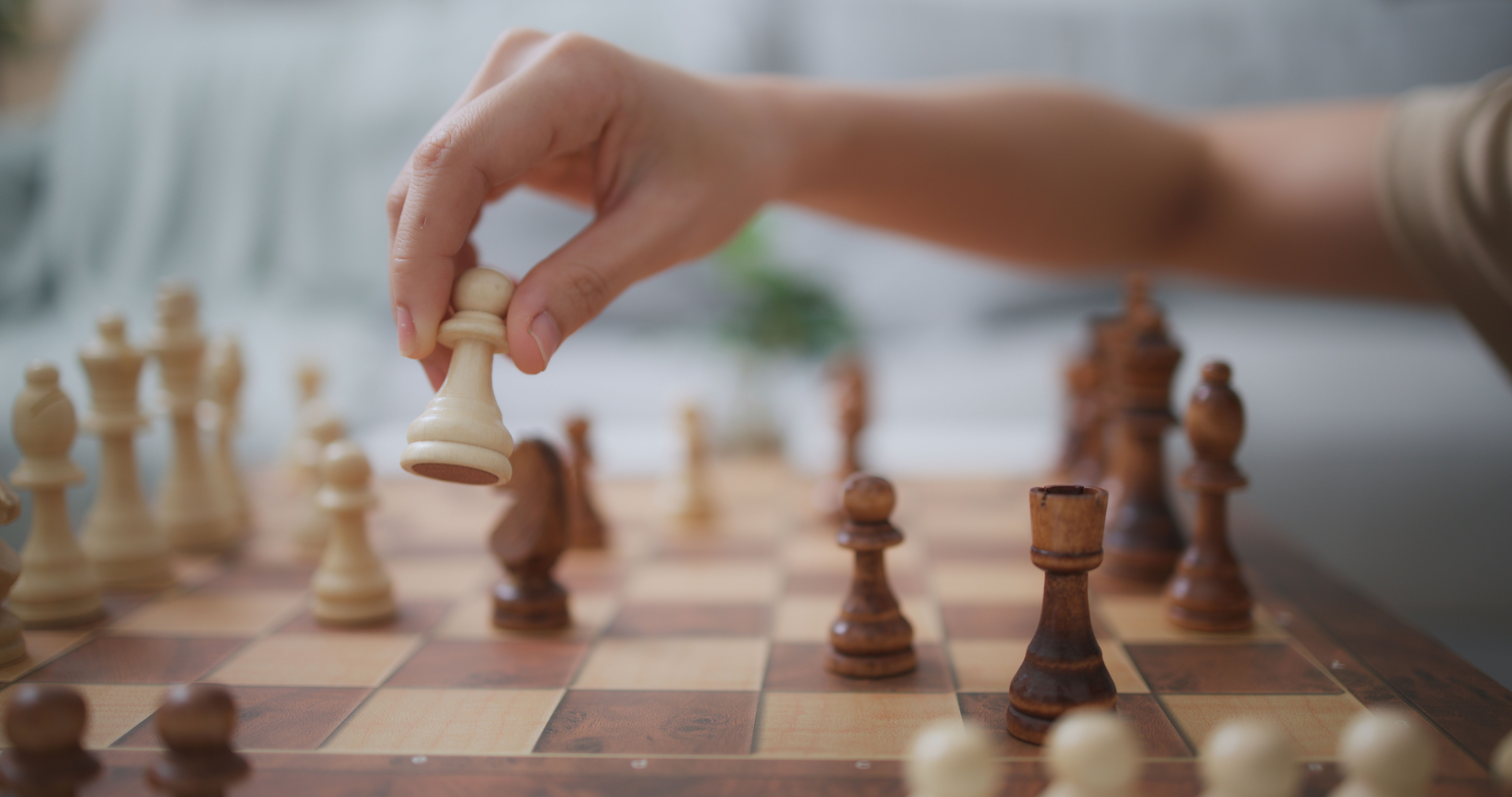 Hands of young woman moving piece on chess board during competition game
