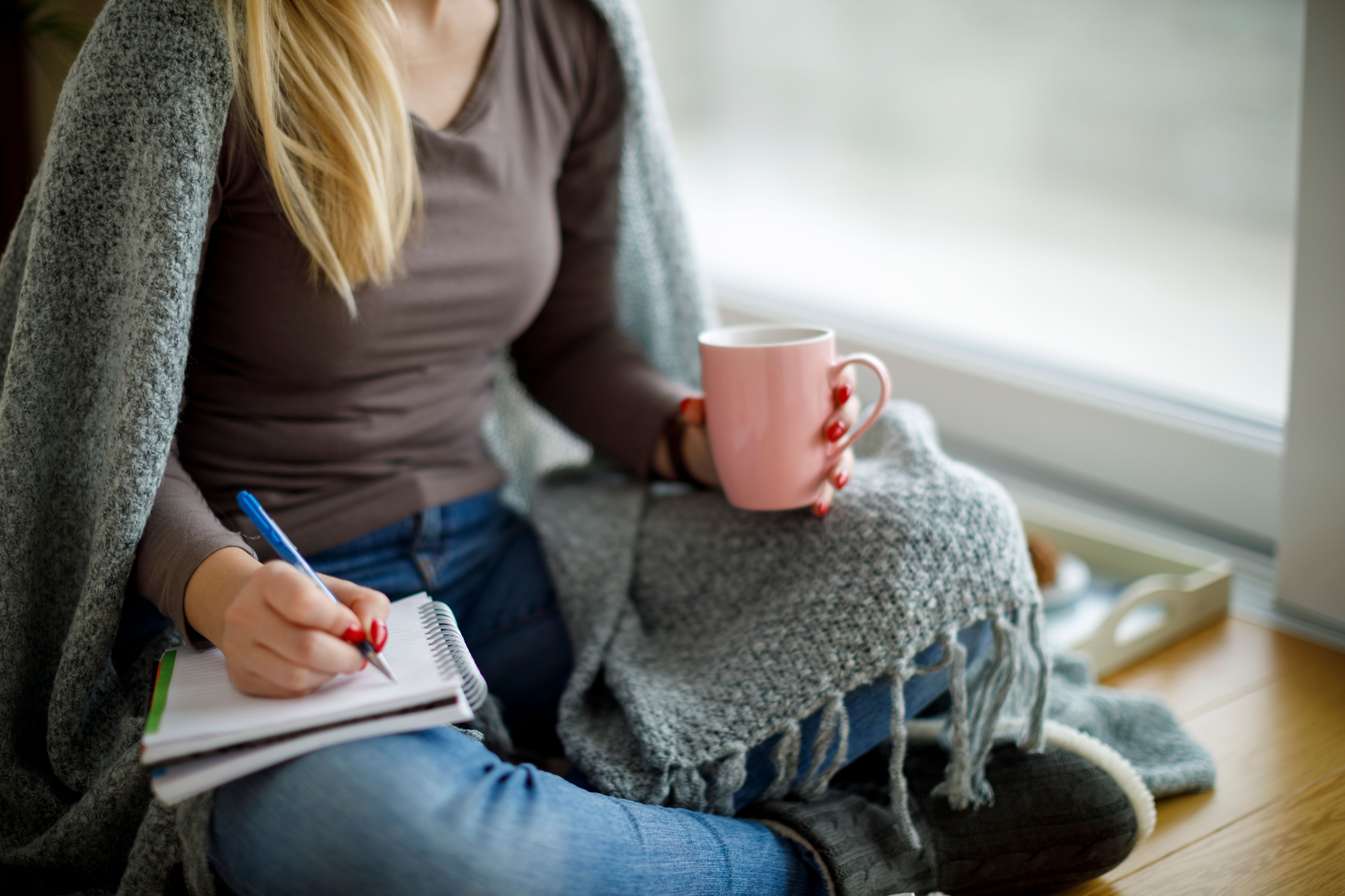 Young woman sitting on the floor and writting notes
