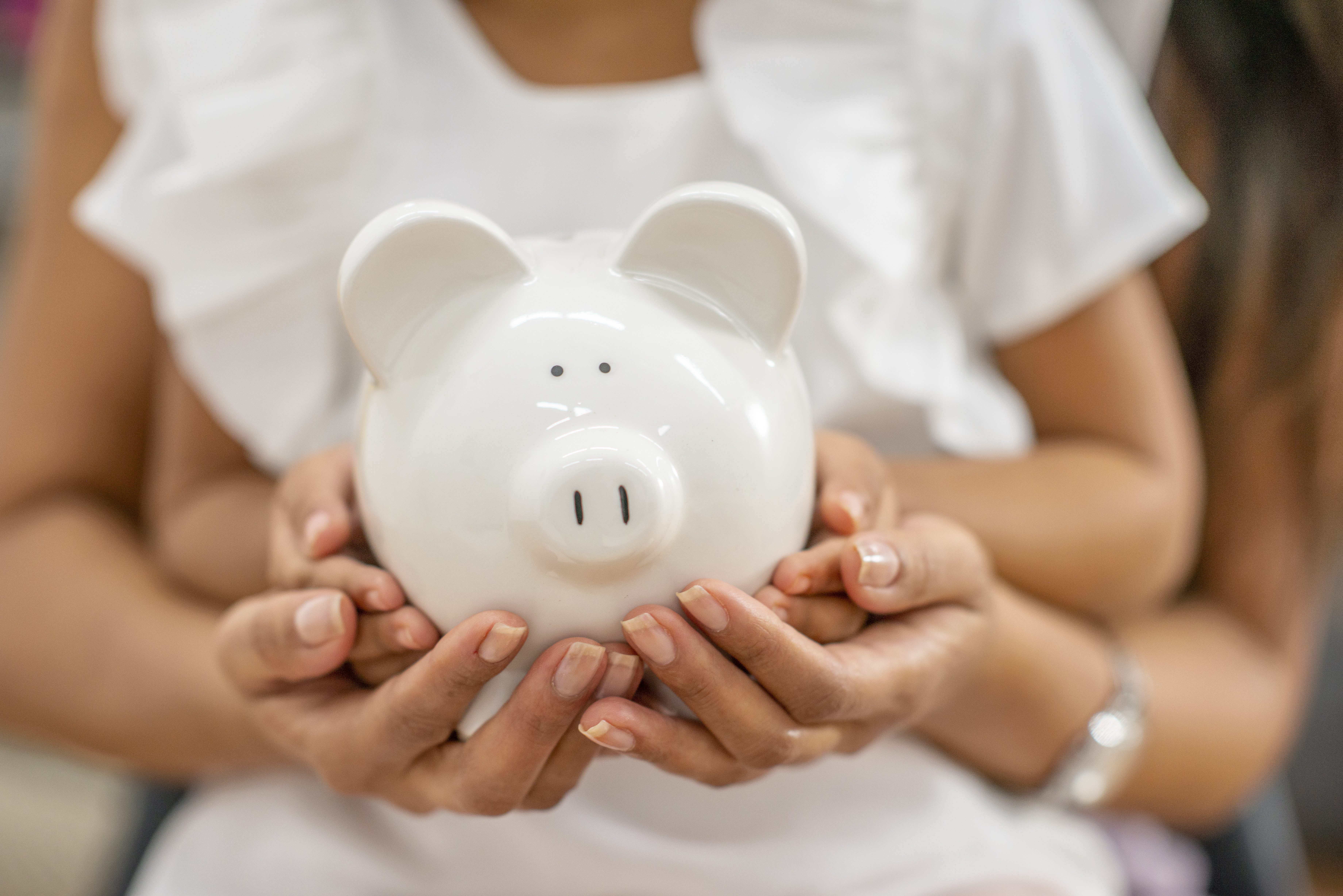 Child and mother holding white piggybank