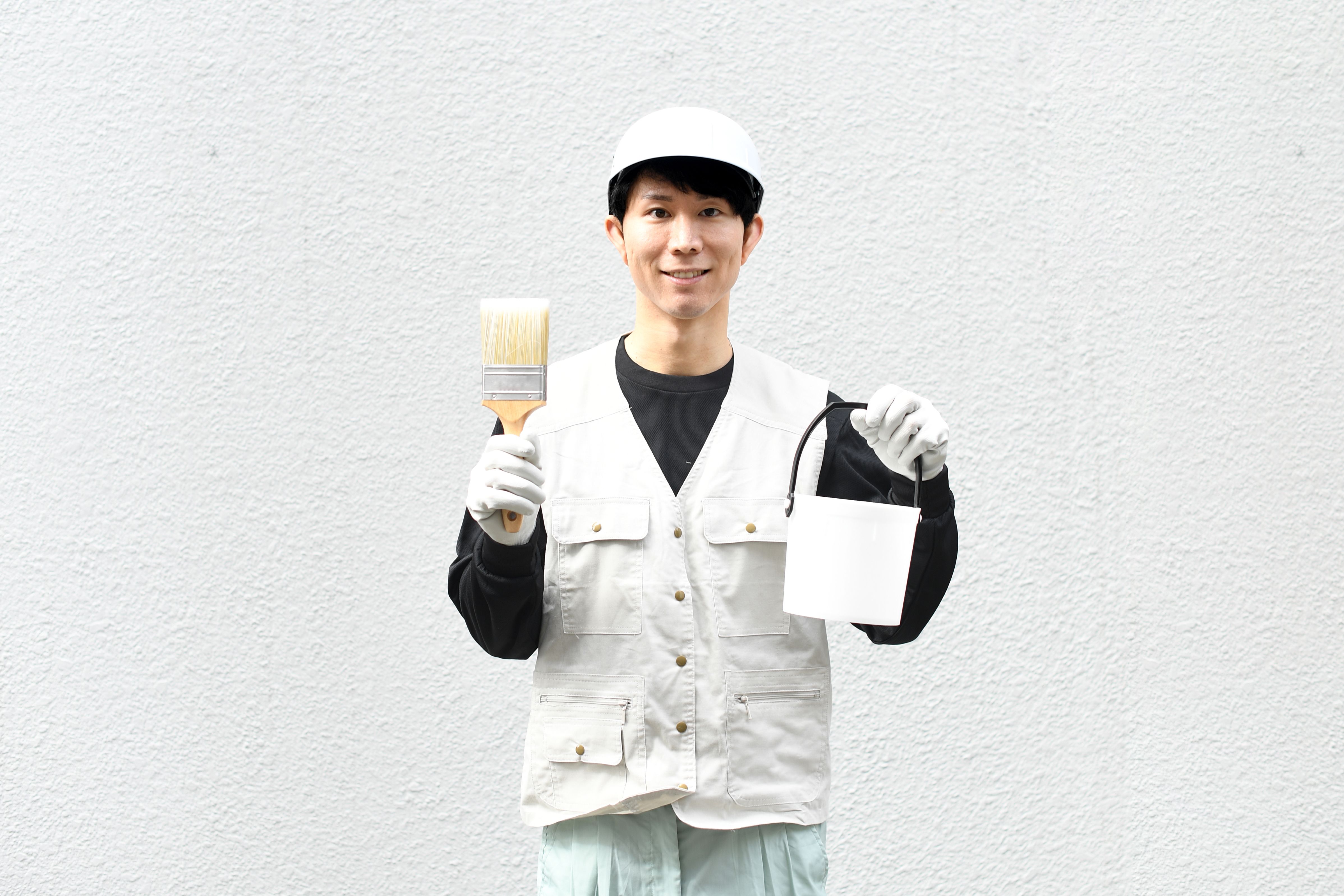 Asian male worker painting exterior walls outdoors