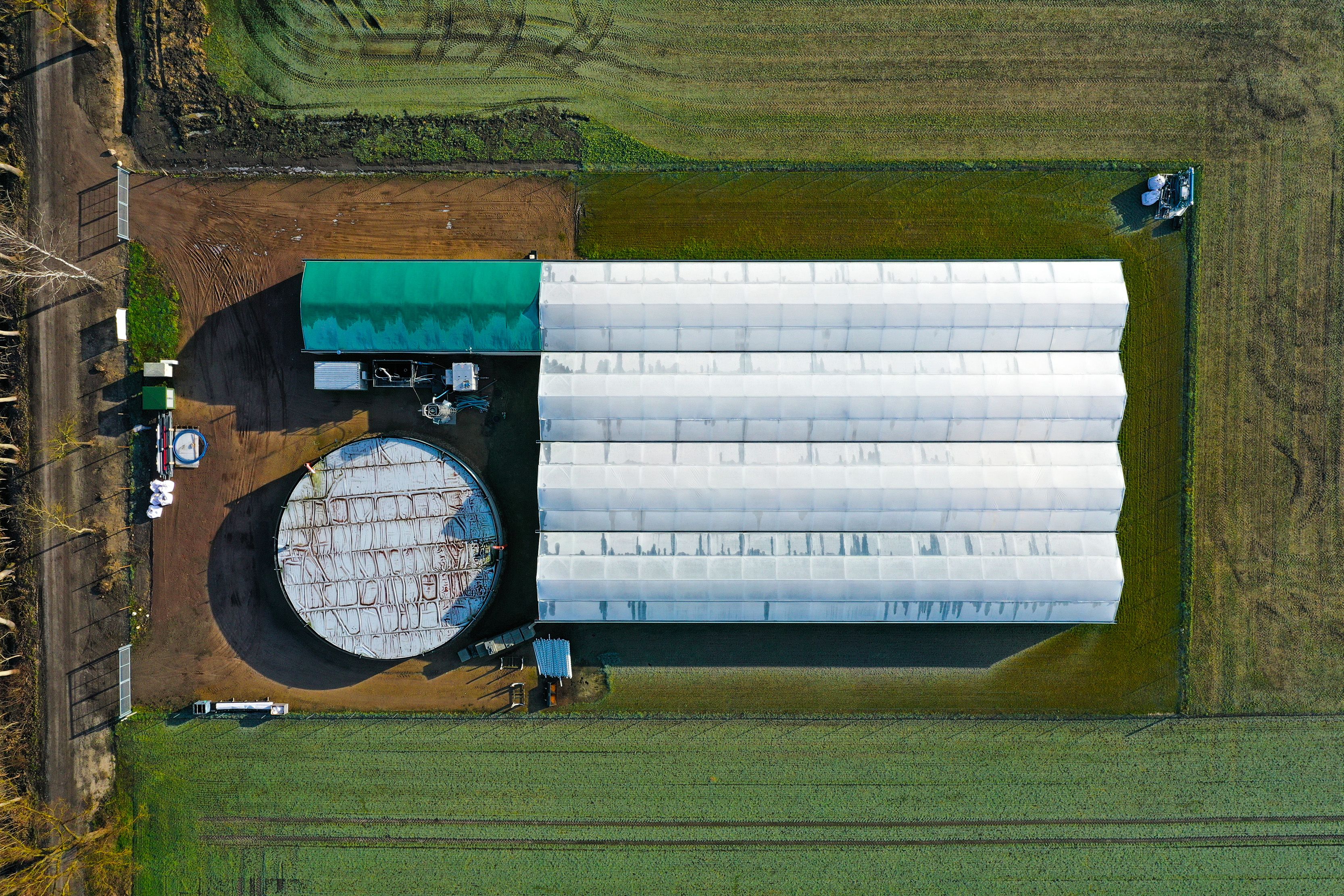 Aerial view of greenhouses and biogas plant in agricultural landscape