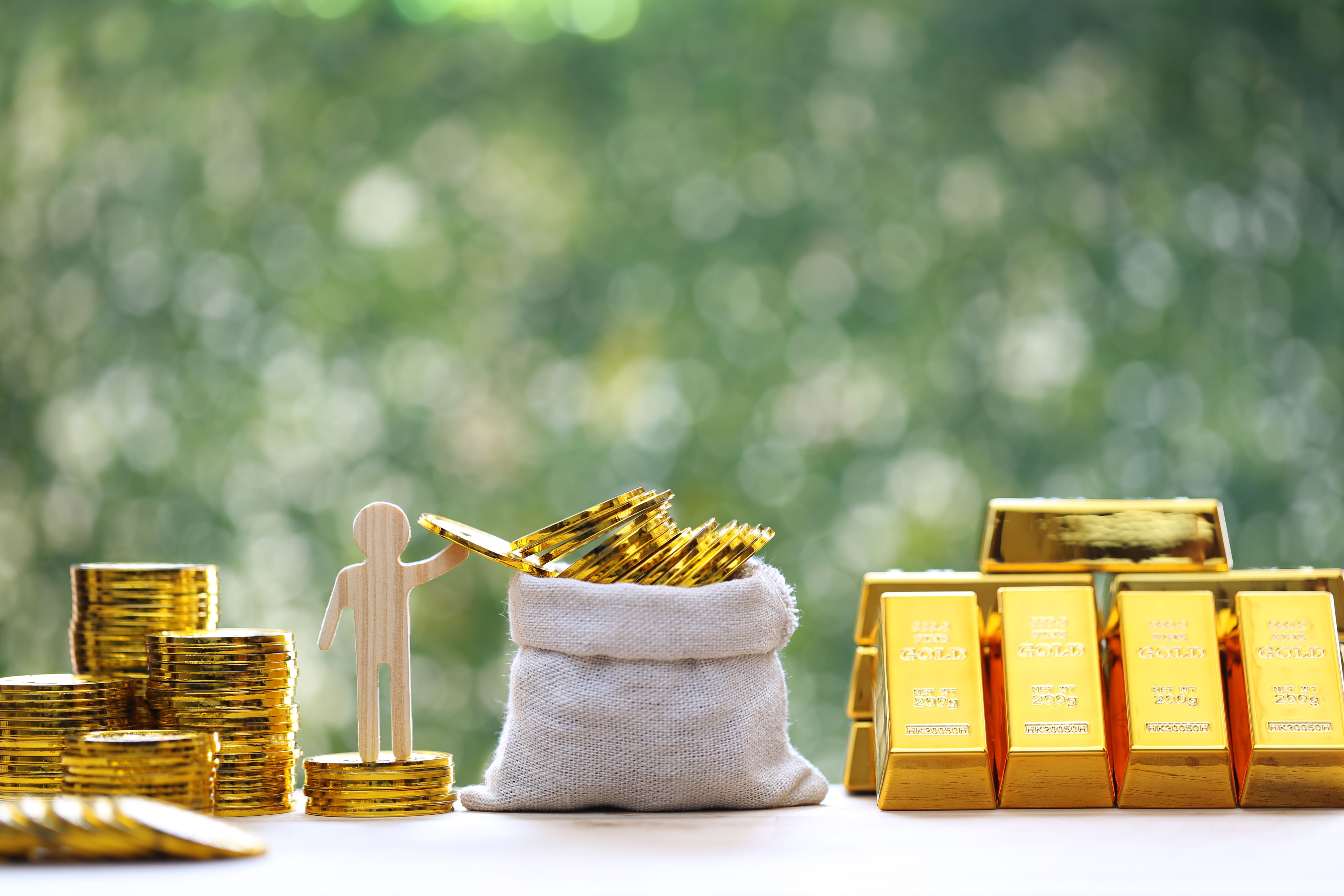 Gold bars and stack of gold coin money in a bag on natural green background,Business investment and financial concept
