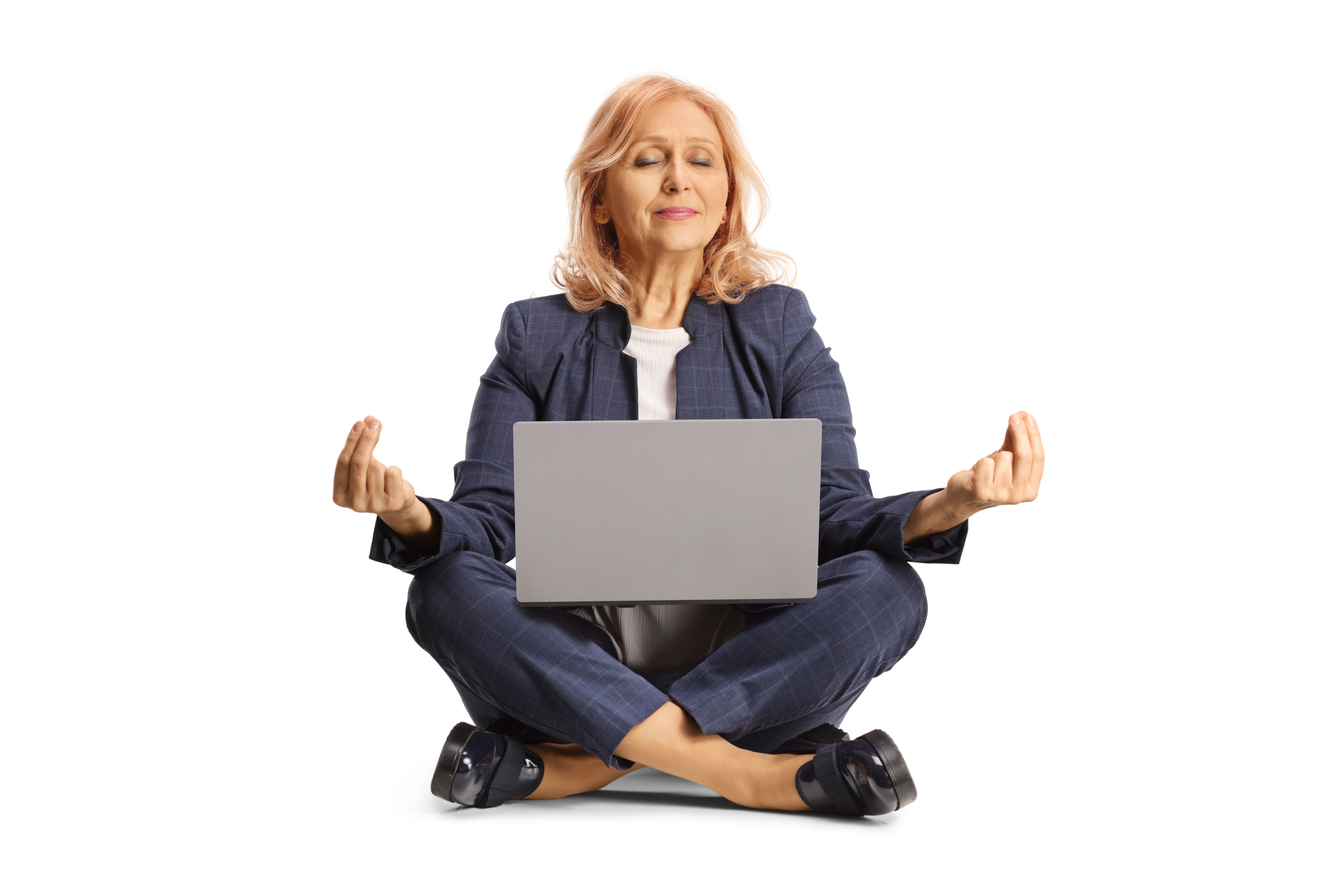 Businesswoman with a laptop computer sitting in a meditation pose with closed eyes