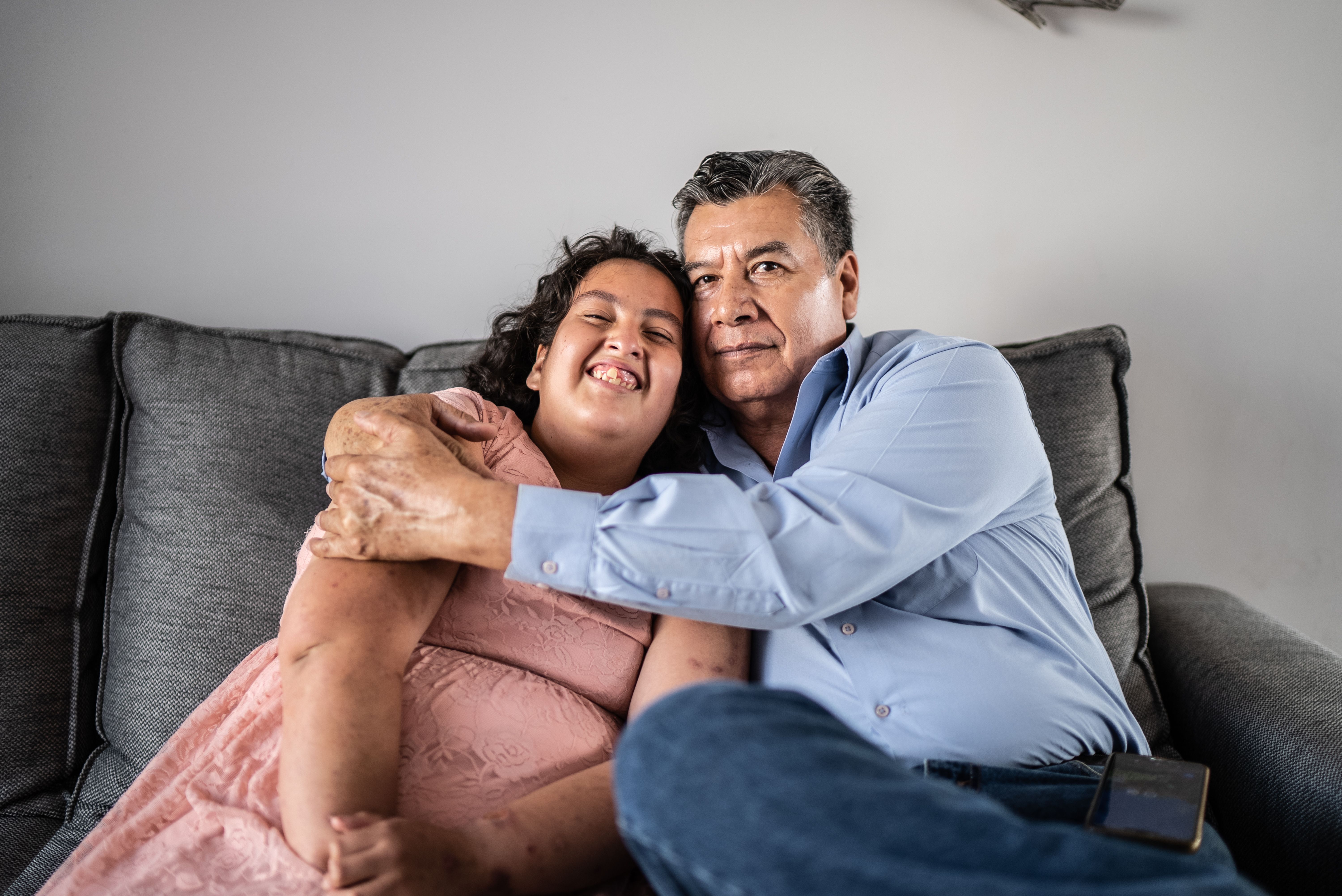 Portrait of father and psychomotor Intellectual disability daughter sitting on the sofa at home