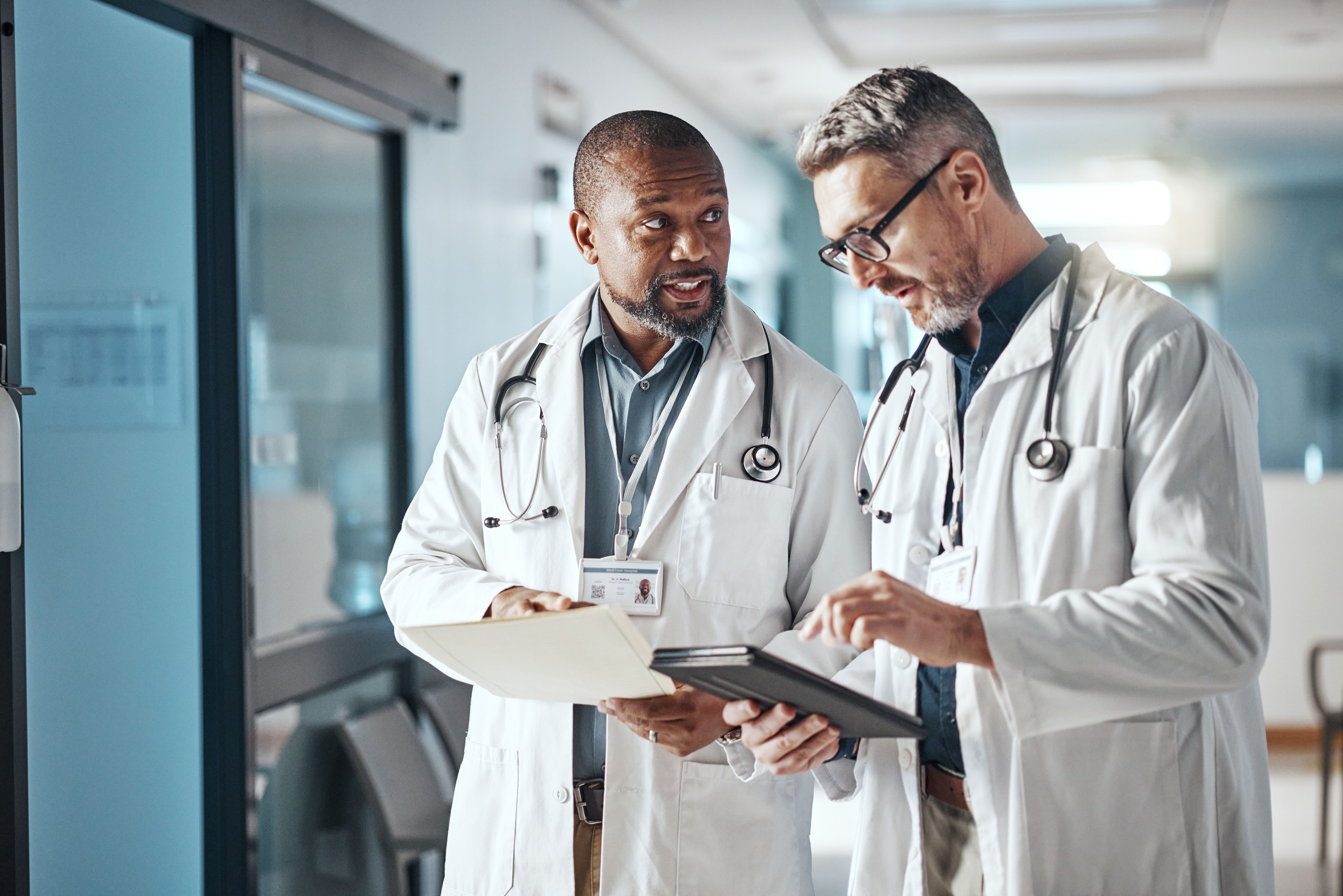 Hospital, trabalho em equipe e médicos com folder, tablet e brainstorming para saúde e administração. Médico, líder e profissional sênior com tecnologia e reunião com documentos e compartilhar informações