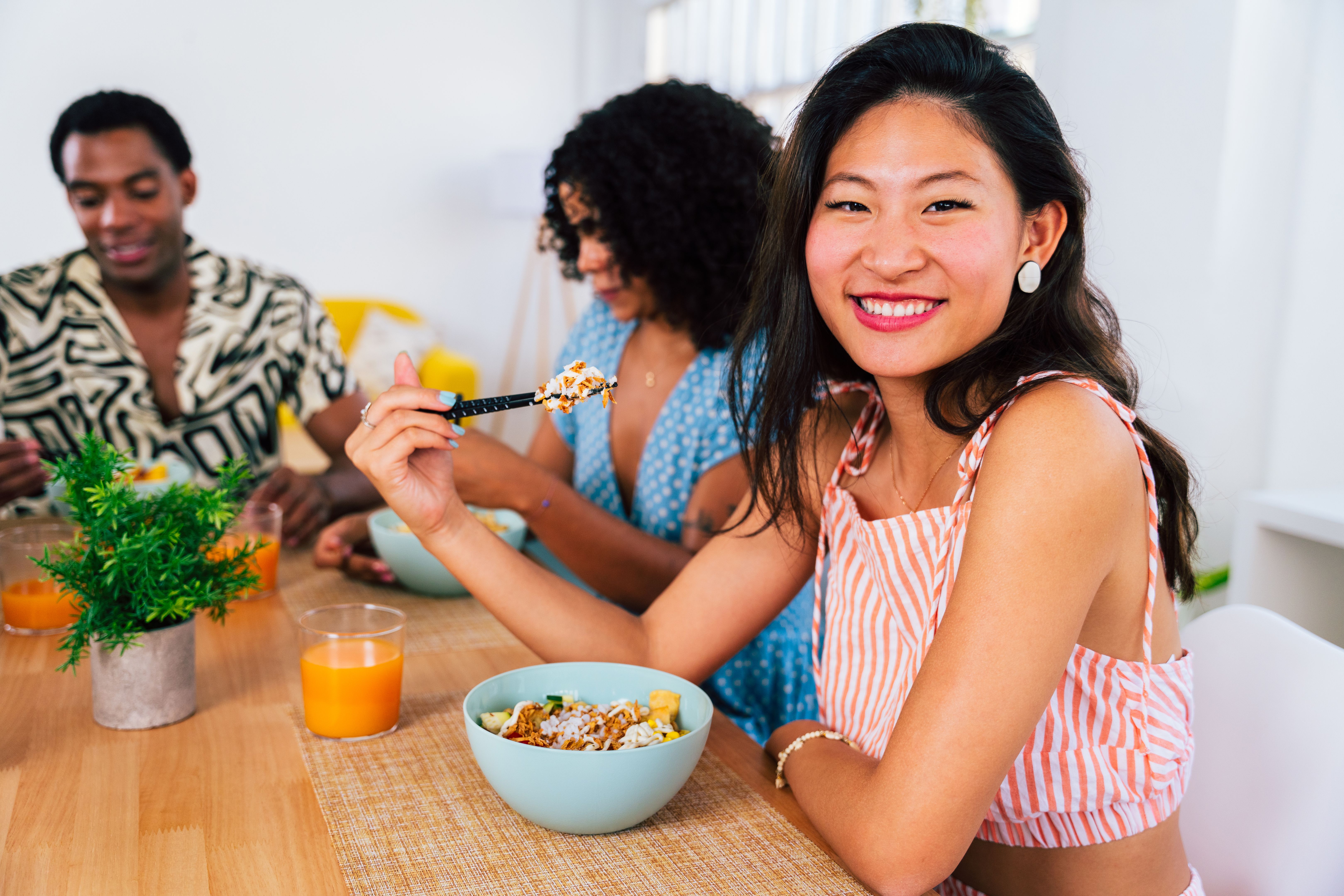 Multiethnic group of young friends meeting at home and eating poke bowls Multiethnic group of young friends meeting at home and eating poke bowls