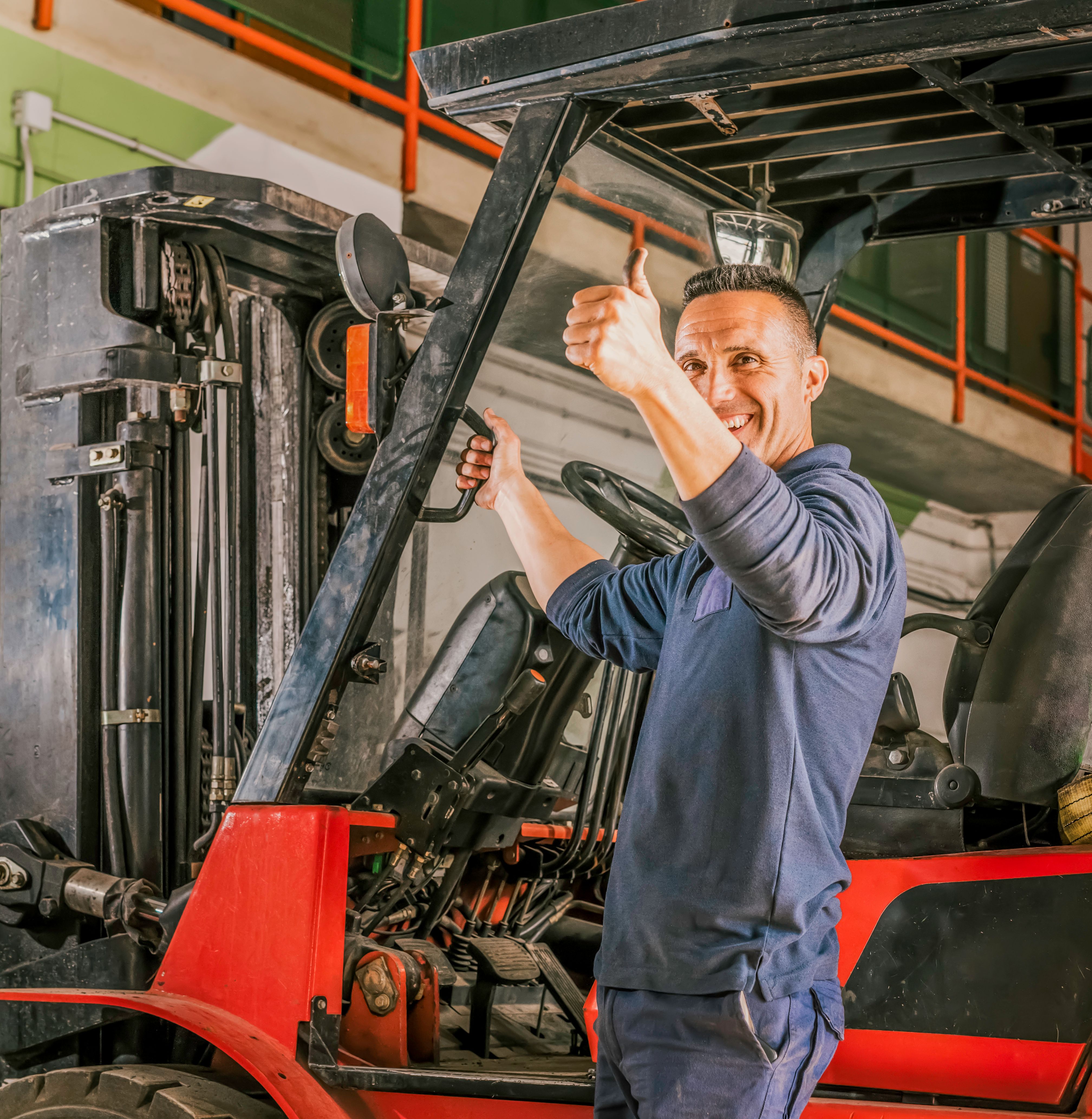 Portrait of a young Latino male smiling and doing a thumb up gesture while getting on a forklift Portrait of a young Latino male smiling and doing a thumb up gesture while getting on a forklift