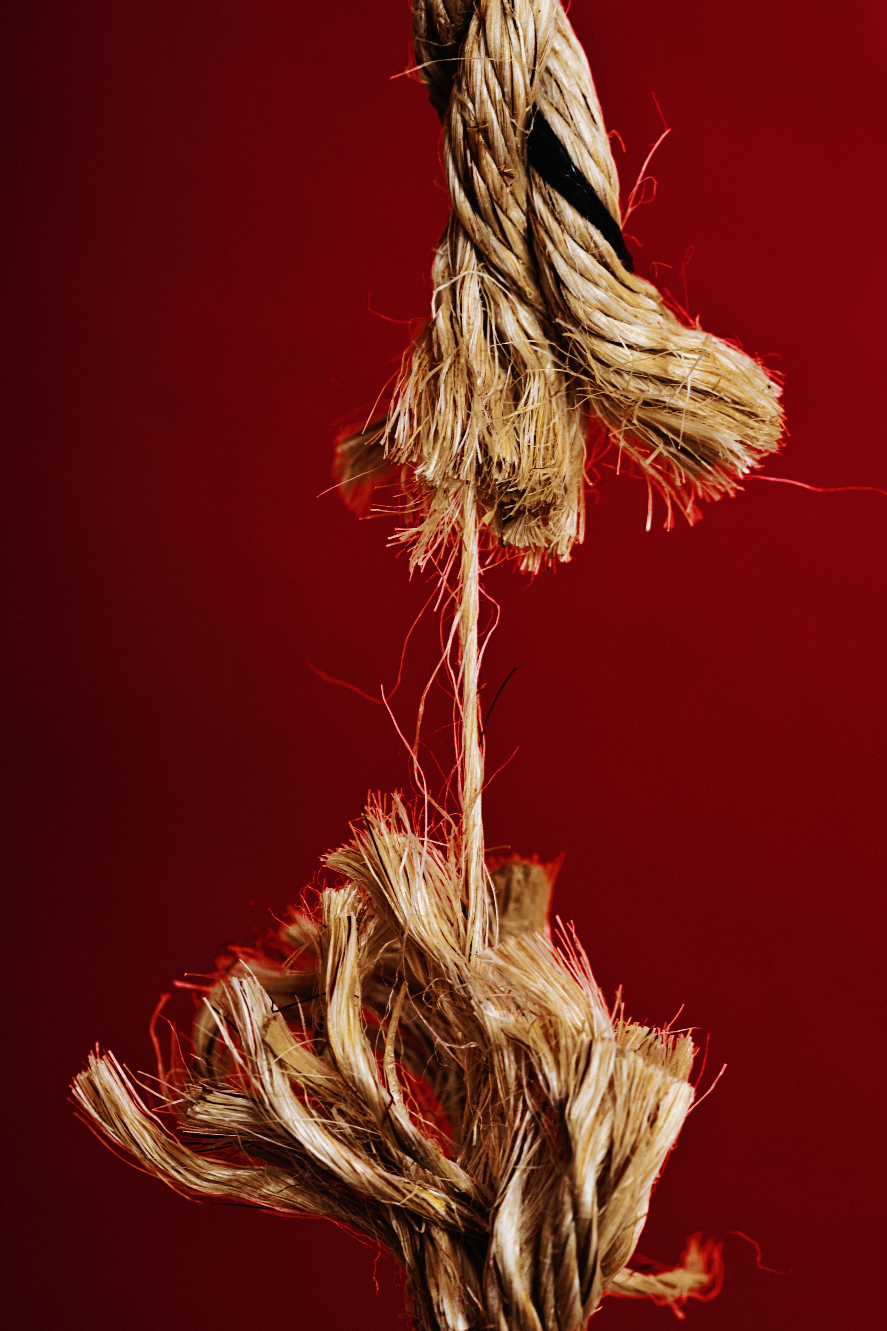 Fraying rope at breaking point, symbolizing danger and weakness