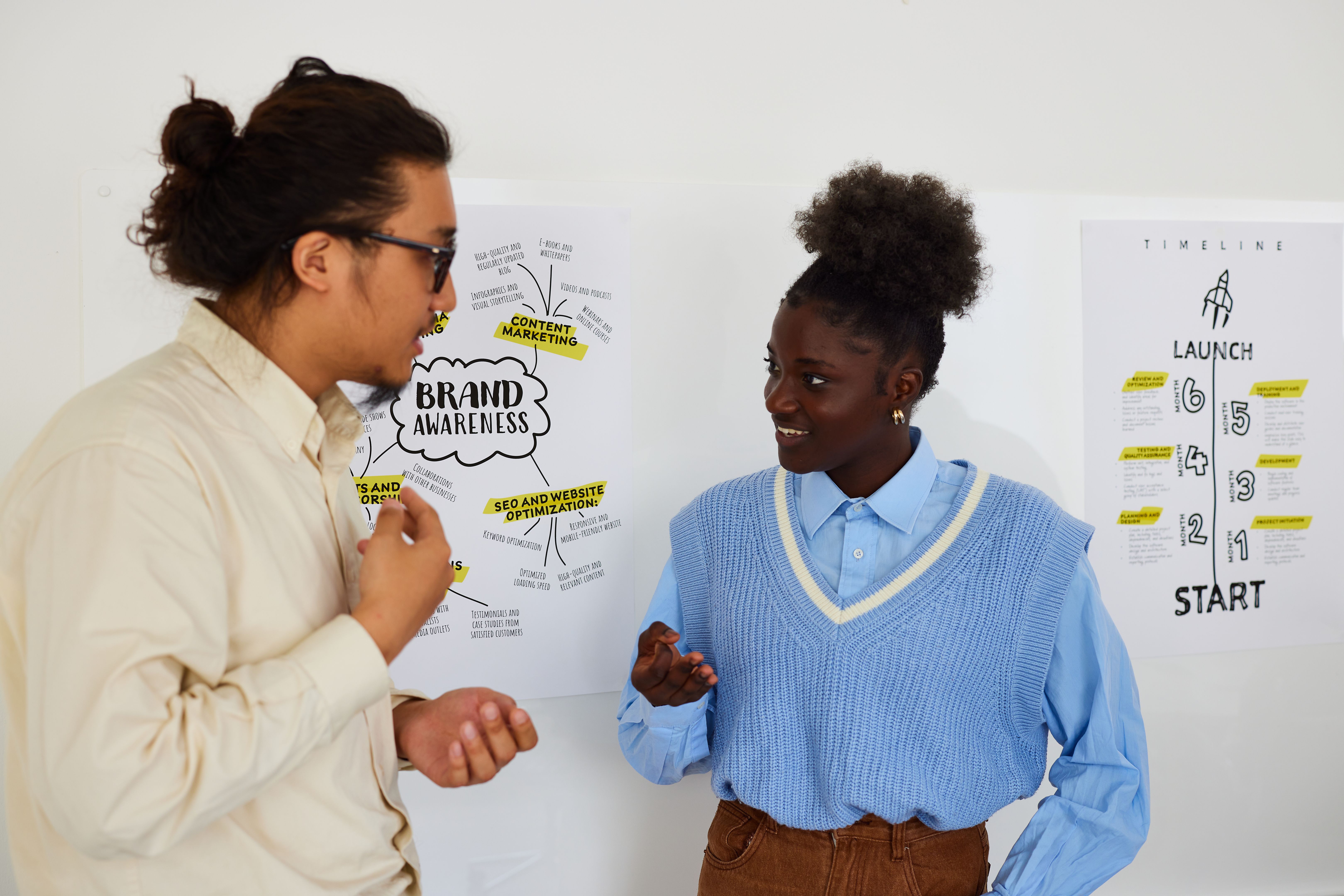 Coworkers with notes on wall discussing ideas in office