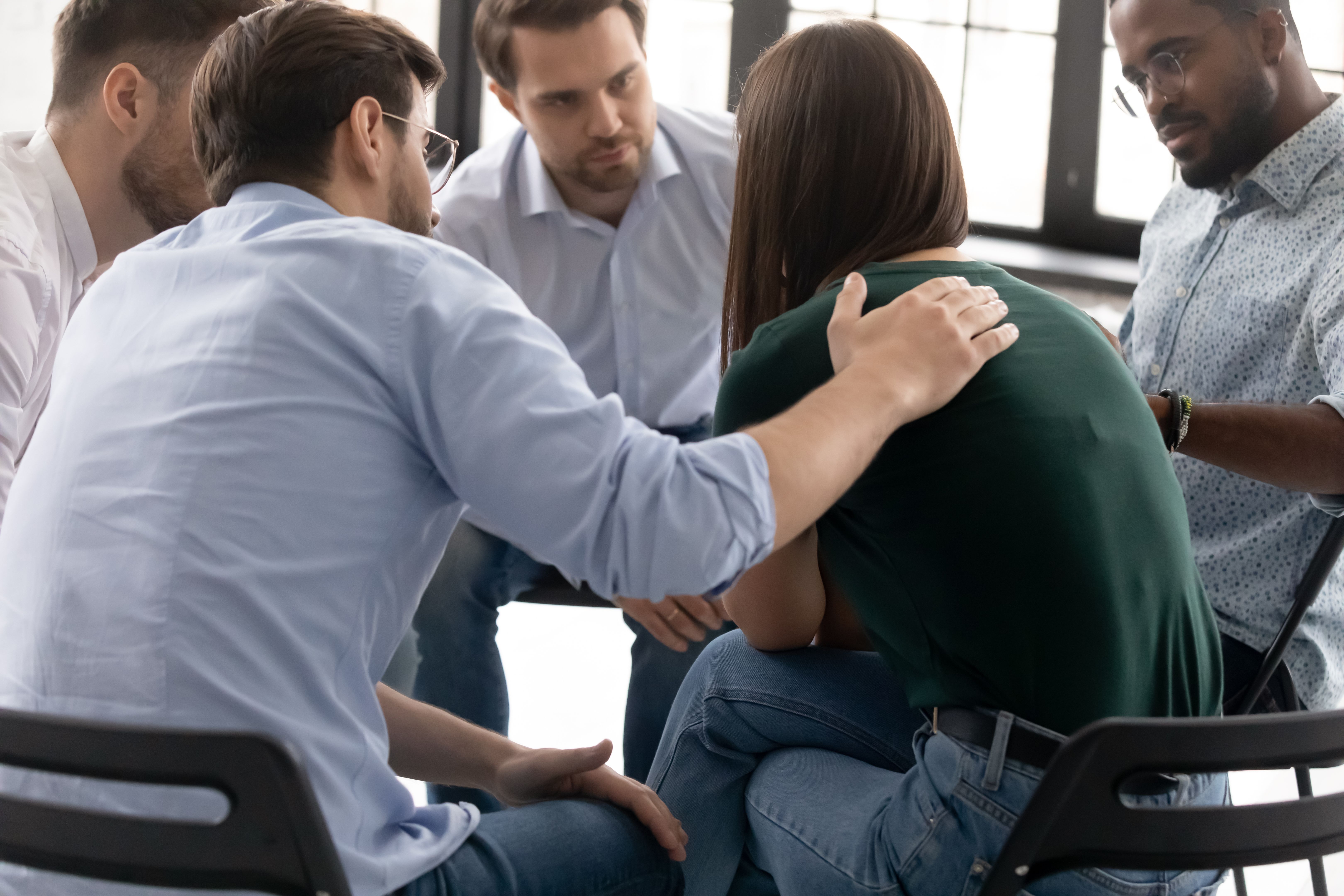 Desesperada chica llorando compartiendo triste experiencia con compañeros de grupo