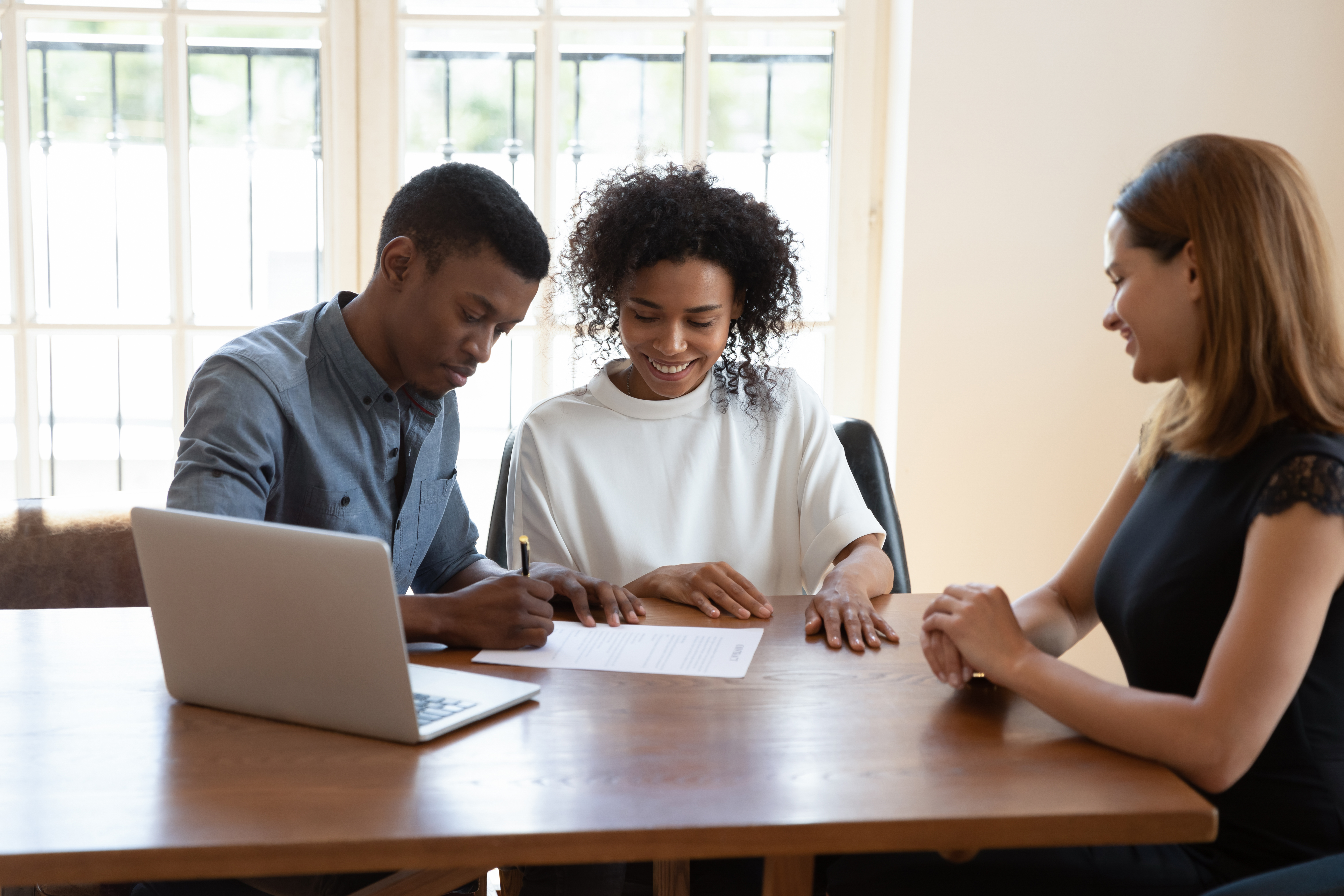Excited african American couple close deal at agent office Excited african American couple close deal at agent office
