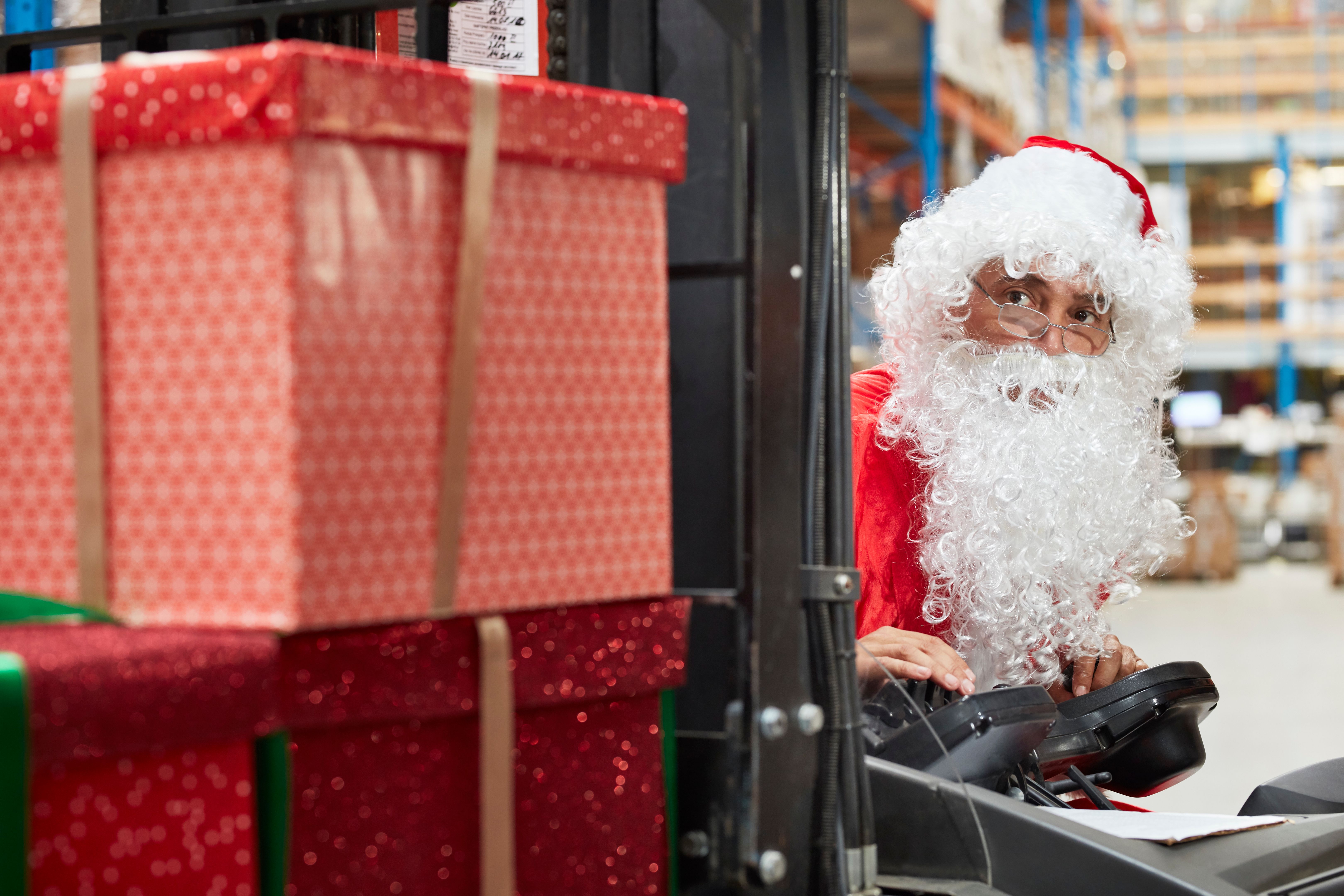 Christmas in a warehouse. Santa claus picking christmas gifts with forklift