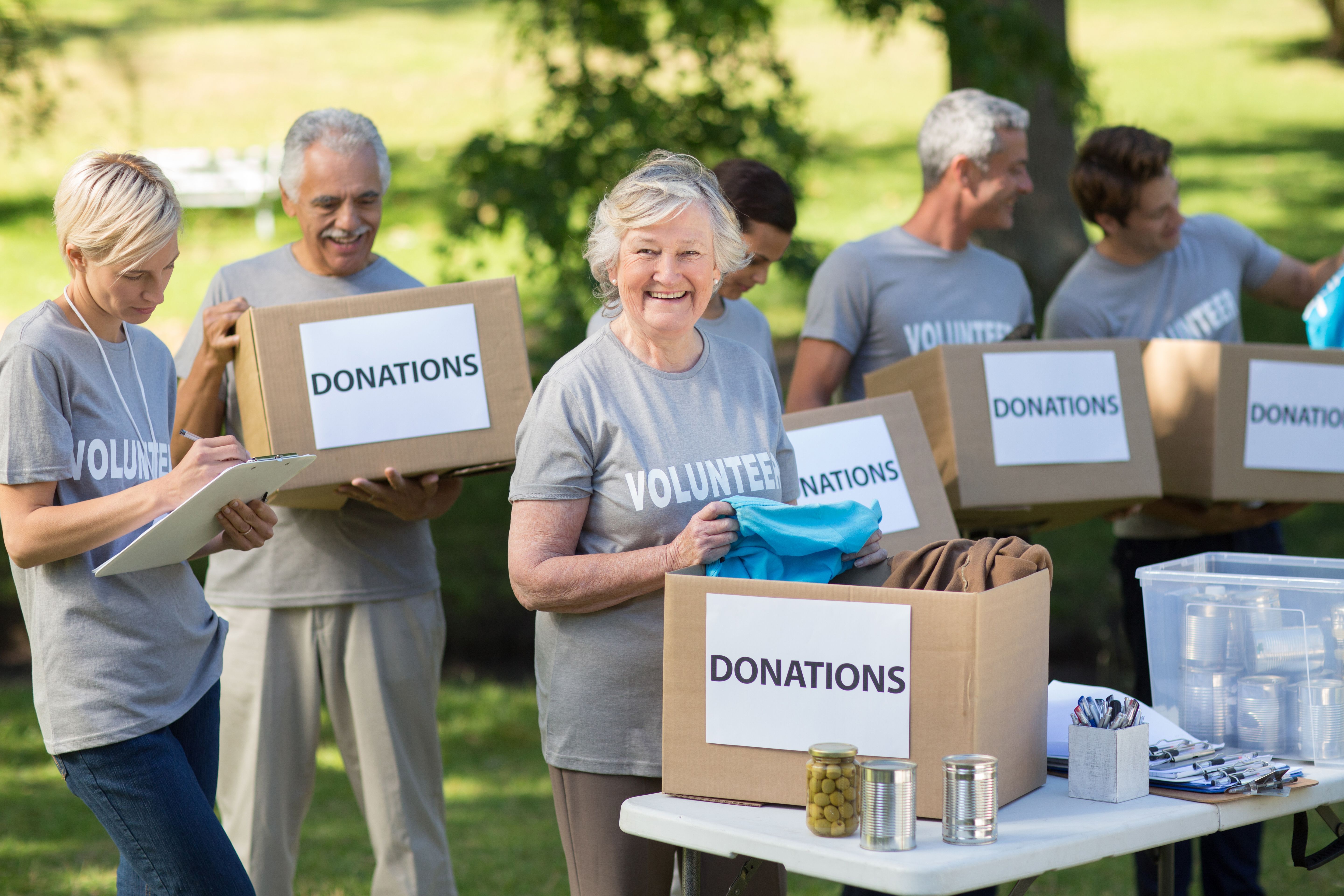 Group of nonprofit volunteers organizing donation boxes during a summer fundraising event, highlighting the importance of compliance and volunteer management.