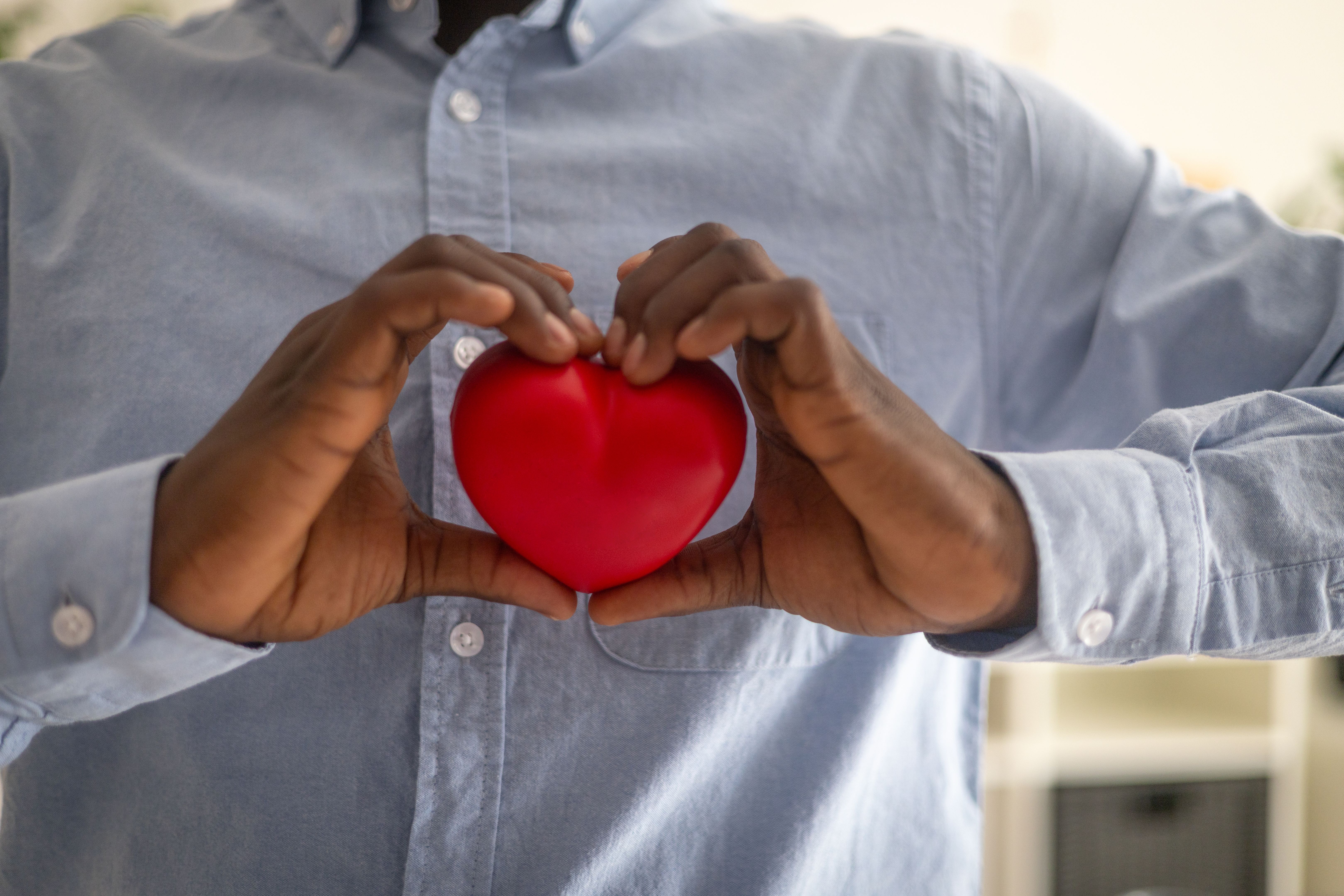 Close-up of hands holding a red heart, illustrating the connection between nonprofit mission, IRS compliance, and maintaining federal tax-exempt status.