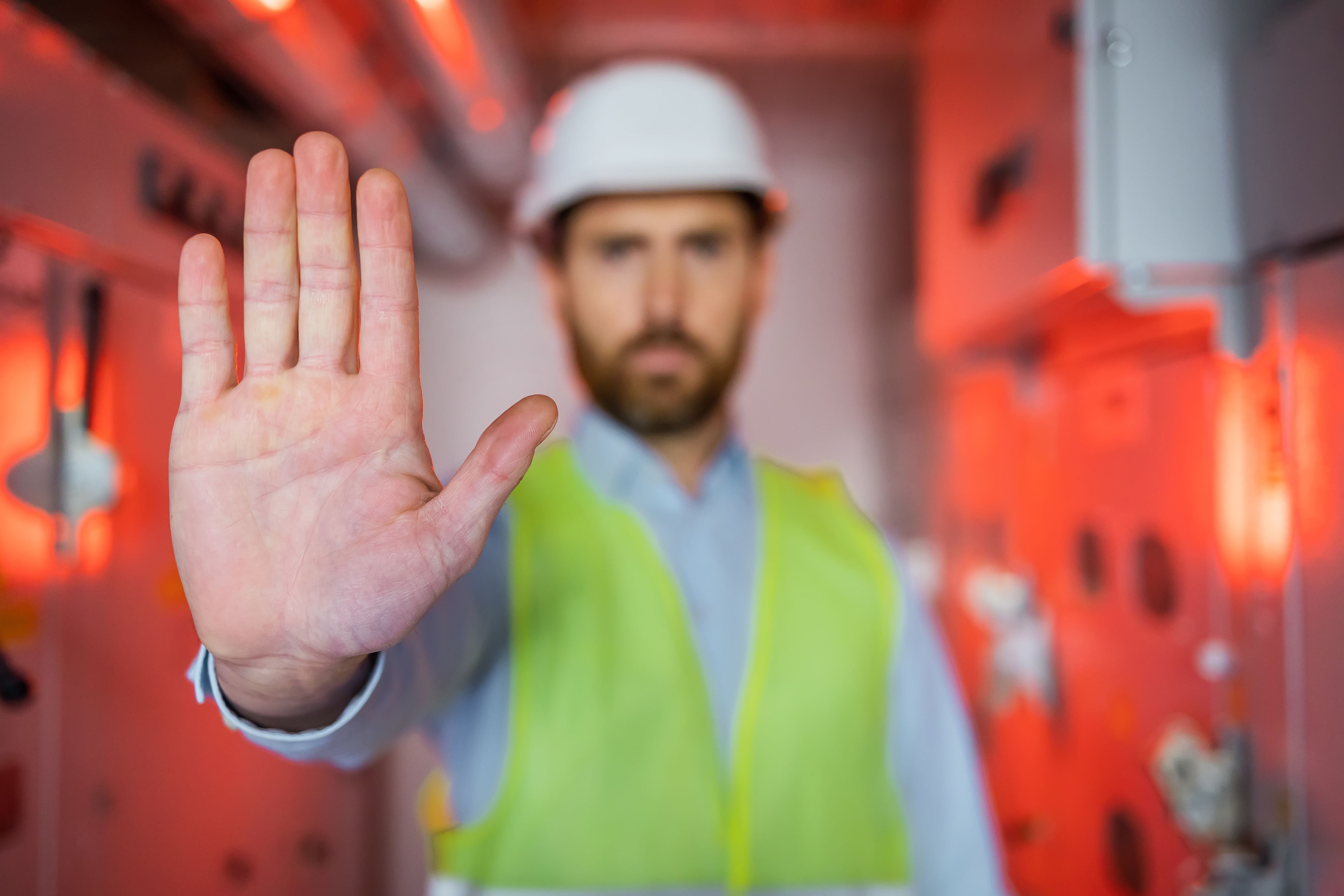 Male Engineer palm Disapproving With No Hand Sign While Standing In The red lighted room