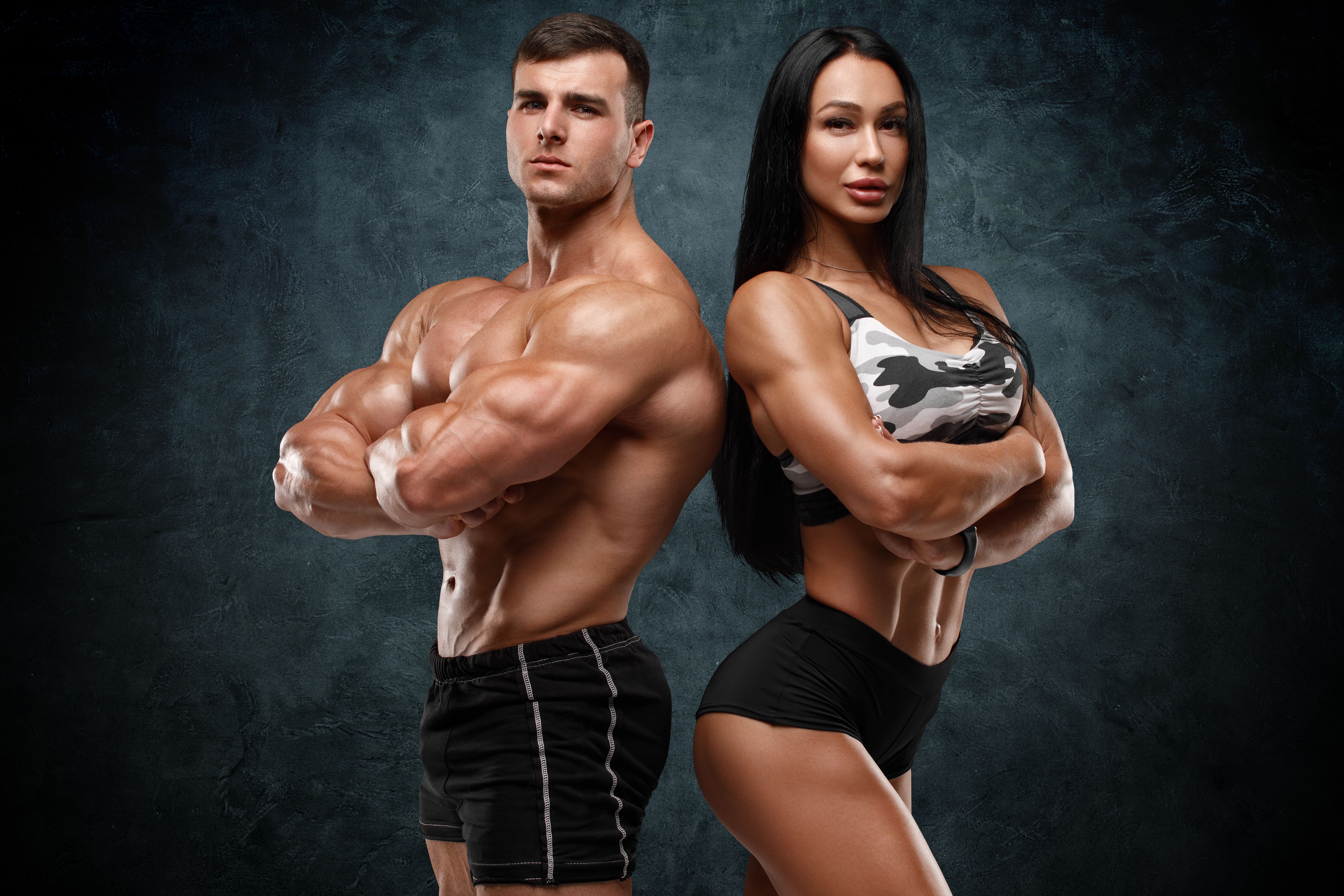 Sporty couple showing muscles. Muscular man and woman Sporty couple showing muscles. Muscular man and woman
