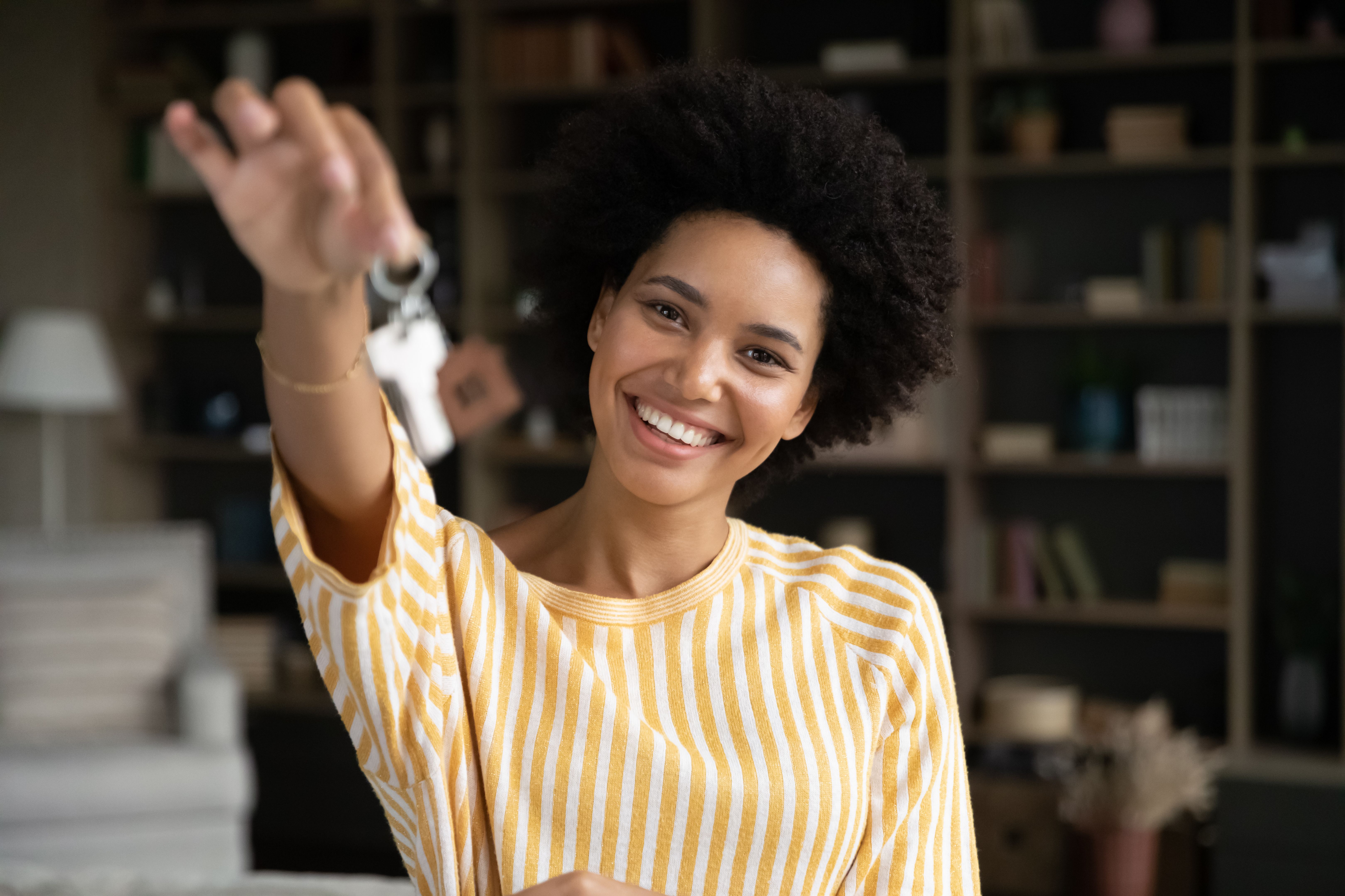Happy joyful young African woman showing keys at camera Happy joyful young African woman showing keys at camera