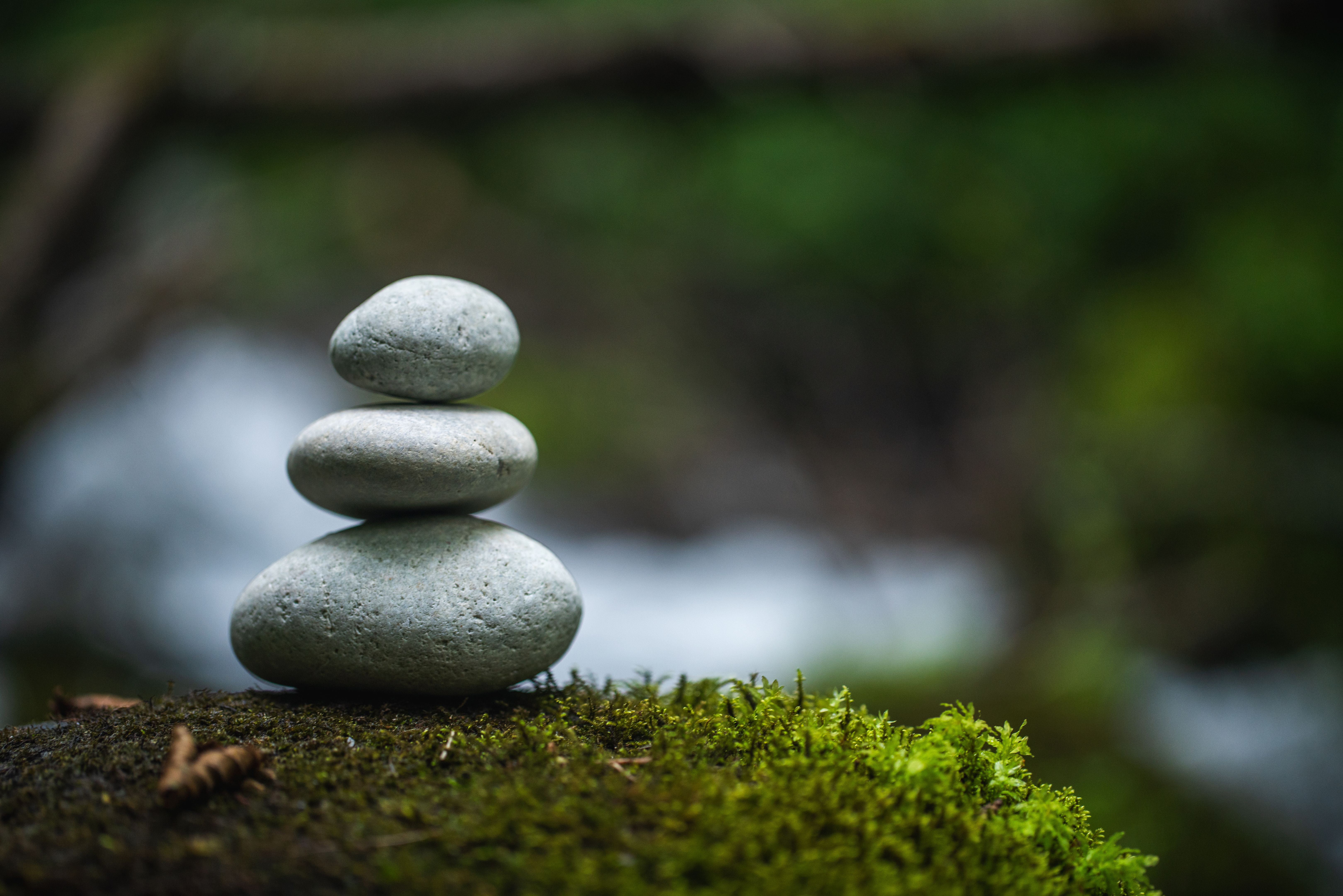 Balanced Stack of Stones on Moss-Covered Surface in Tranquil Natural Setting