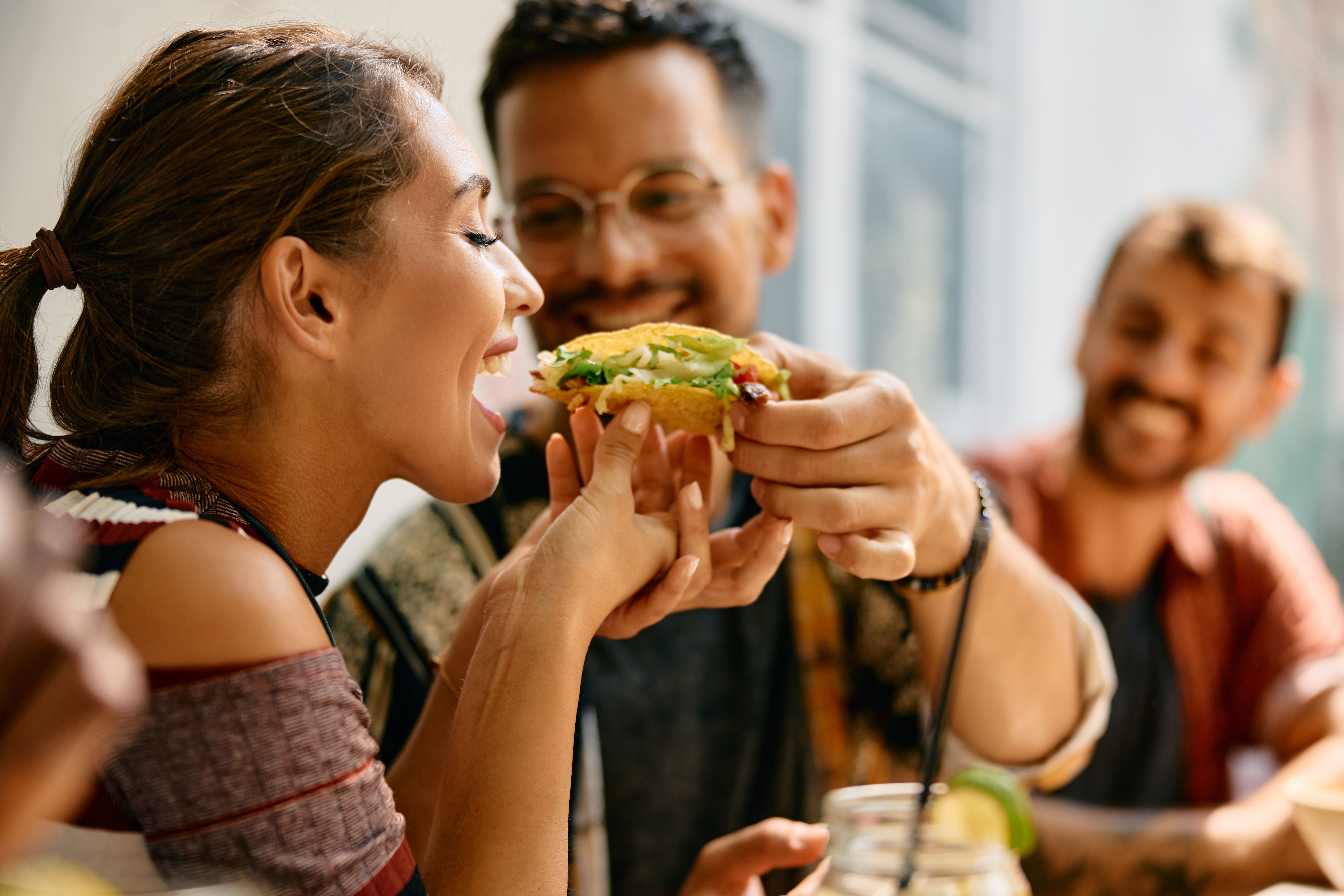 Happy couple sharing a tacos in a restaurant..