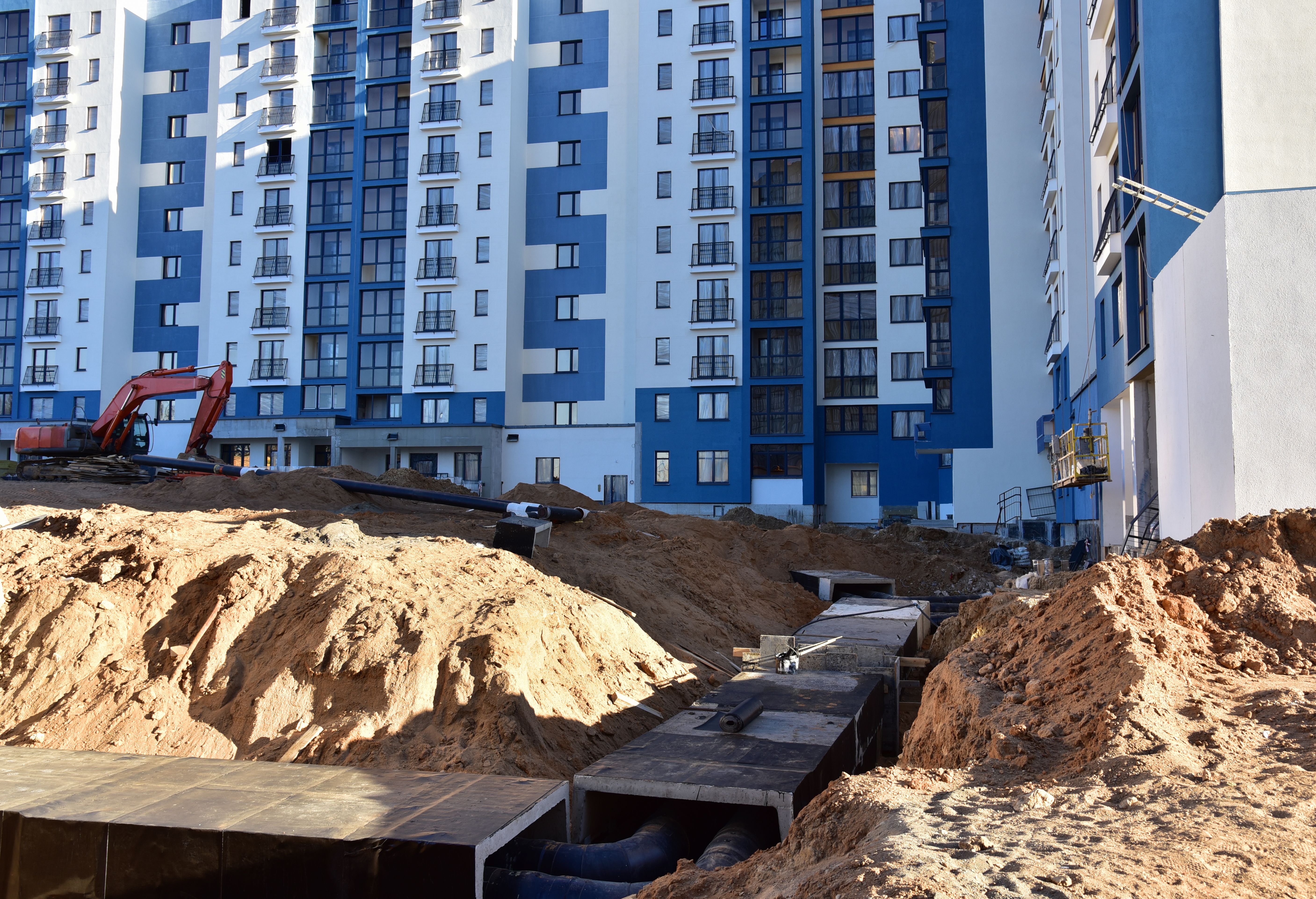 Laying heating pipes in a trench at construction site. Install underground storm systems of water main and sanitary sewer. Cold and hot water, heating and heating system of apartments in the house