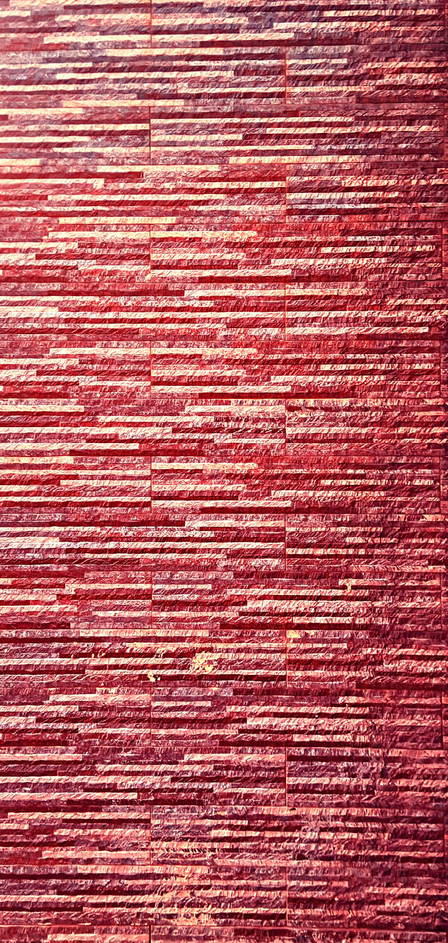 Picturesque, colorful and elegant facing of the wall of the fence, made of bonded thin plates of artificial granite, marble or other stone-forming material