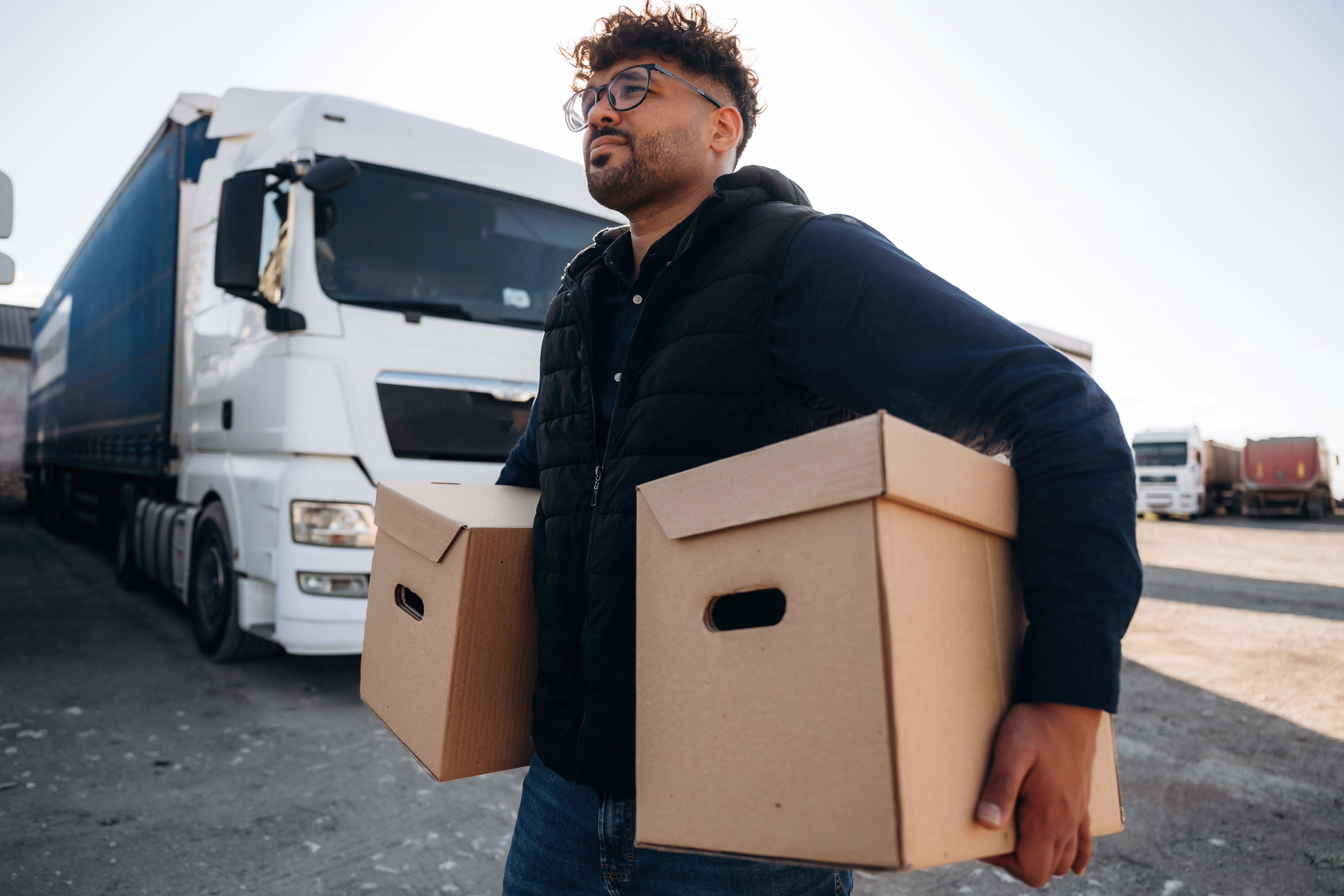 The delivery is in the boxes. Male worker is near truck outdoors