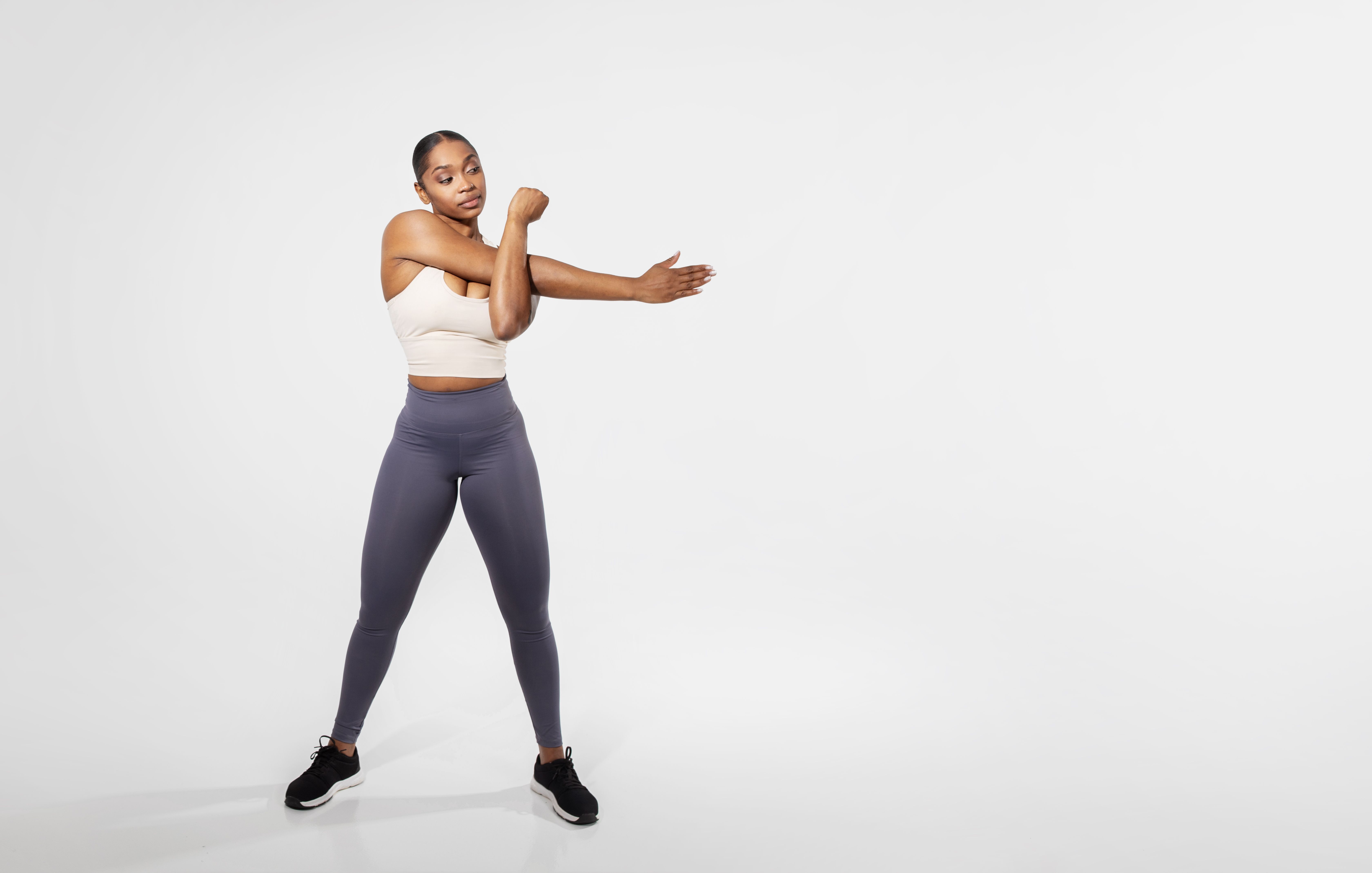 Full length of black fitness woman stretching arms training, studio